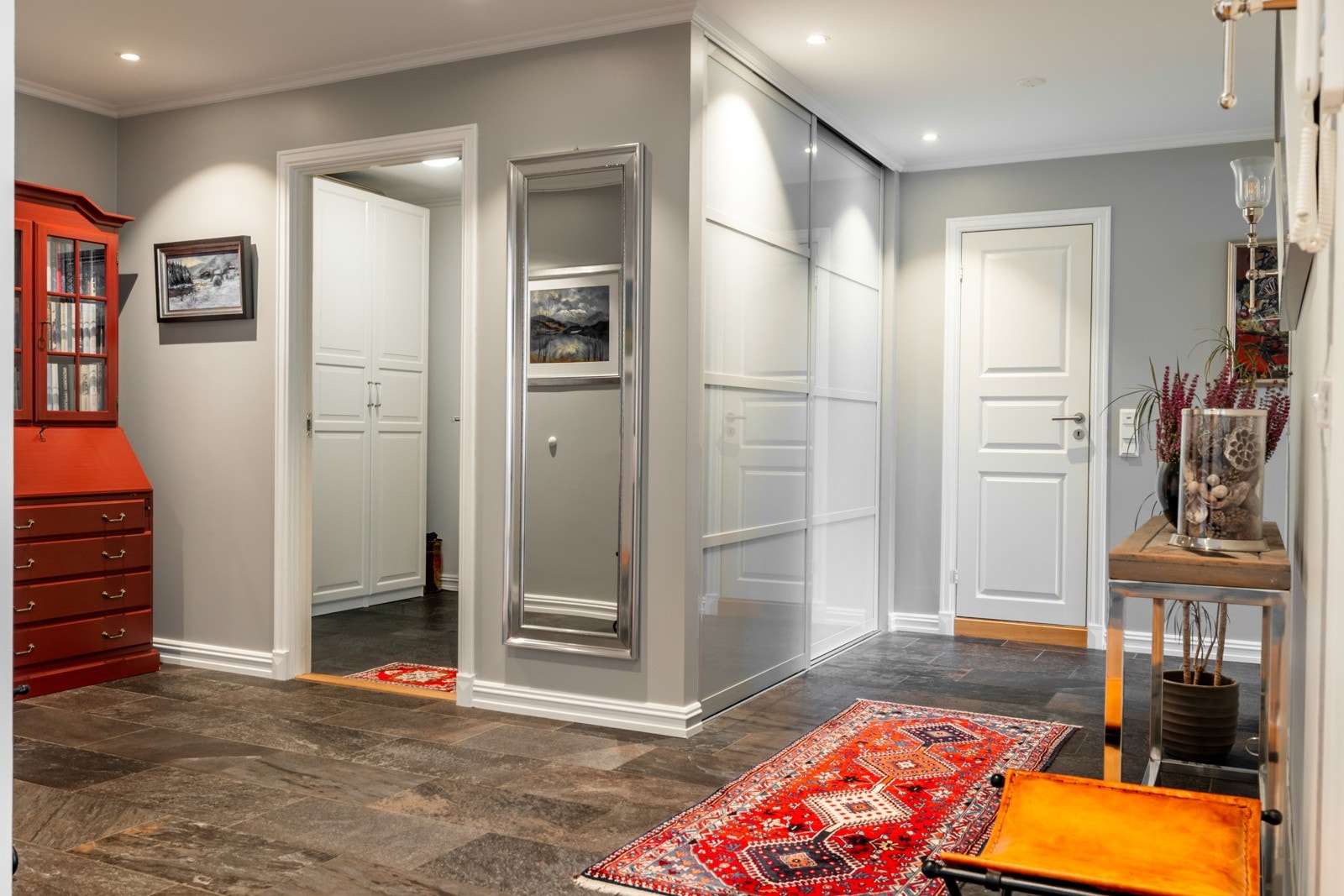 Entreen er svært innbydende med delikate fliser på gulv og glatte, gråmalte veggflater. Entréen har også lun gulvvarme, downlights som gir behagelig belysning og skyvedørsgarderobe. Galleribilde