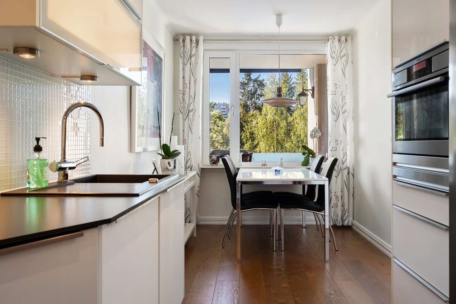 For øvrig har kjøkkenet lekker 1-stavs eikeparkett fra Kährs og varmefolie under parketten. I tillegg har kjøkkenet glatte, lysmalte overflater kombinert med lyse mosaikkfliser. Galleribilde