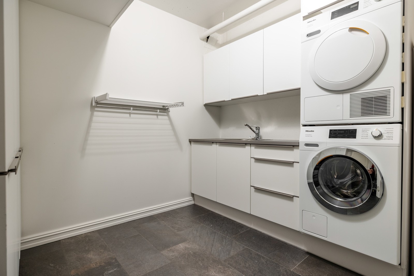 Leiligheten har et romslig vaskerom innredet med flere skap og benkeplate med nedfelt skyllekum. I tillegg er det opplegg for vaskemaskin og tørketrommel i søyle. Galleribilde