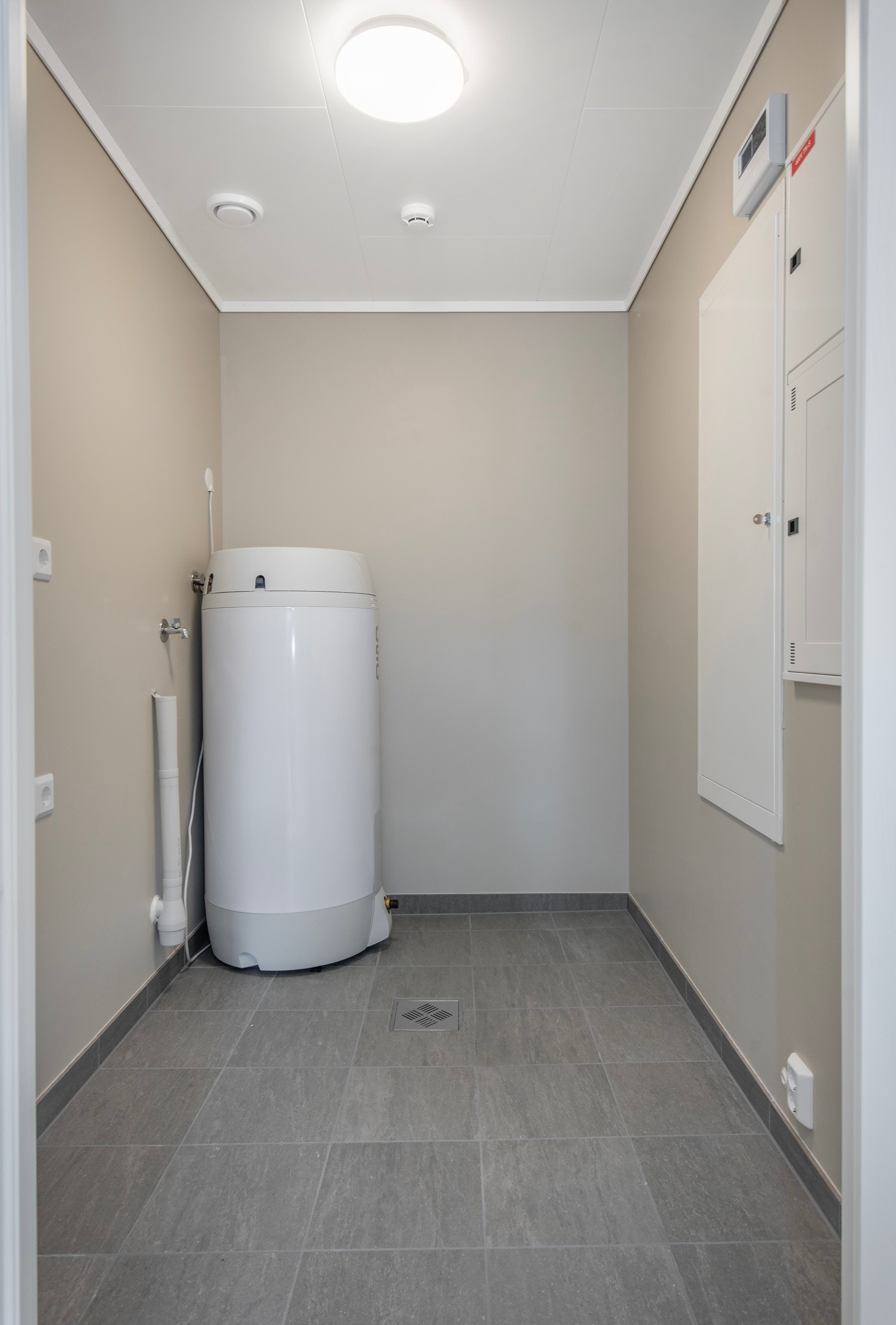 Et praktisk vaskerom flislagt gulv og opplegg for vaskemaskin. Galleribilde