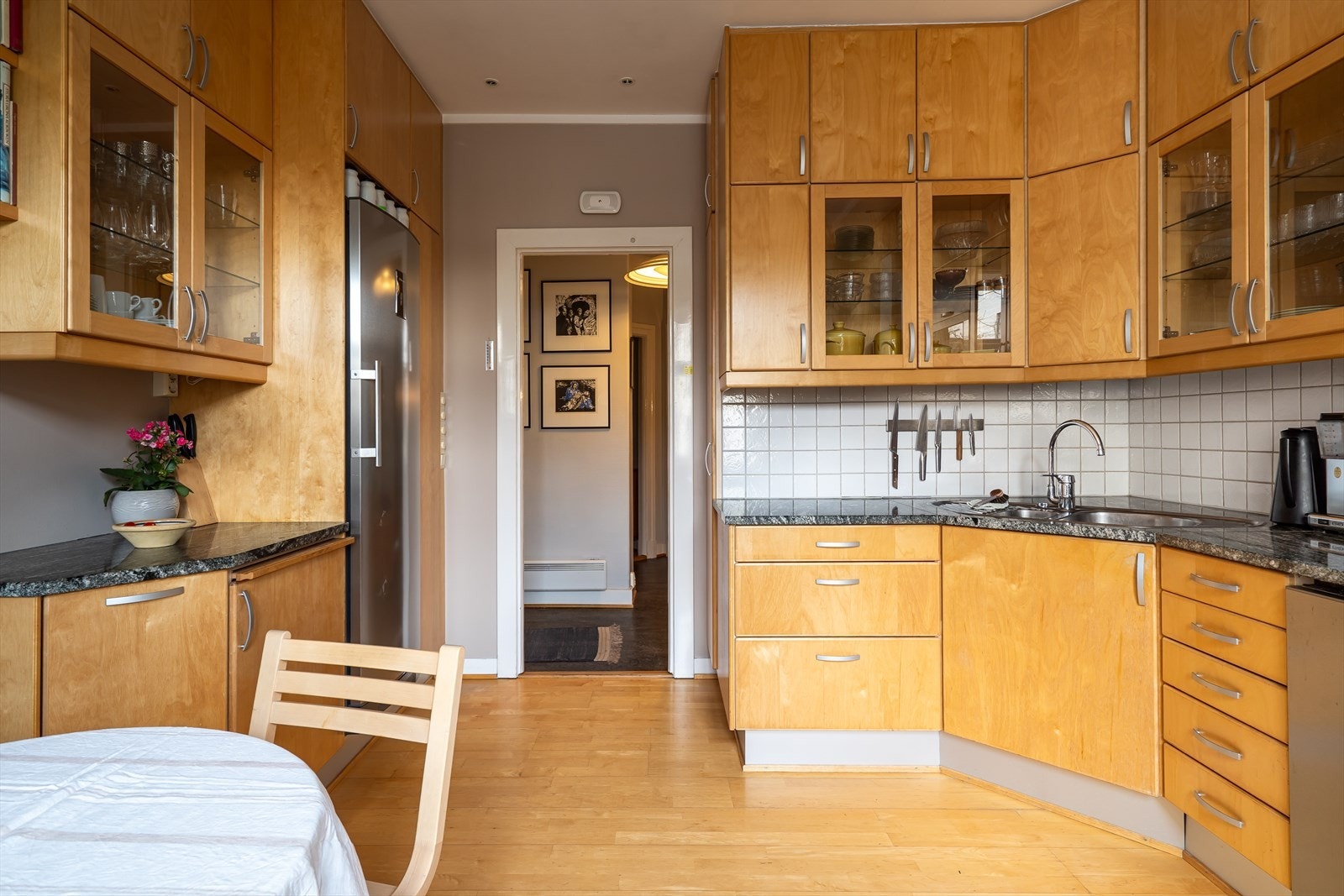 Finerte kjøkkenfronter og benkeplate i stein. Kjøkkenet er utstyrt med en integrert induksjonsplatetopp og stekeovn, samt opplegg for oppvaskmaskin. Over stekesonen finner du en ventilatorhette i stål. Galleribilde