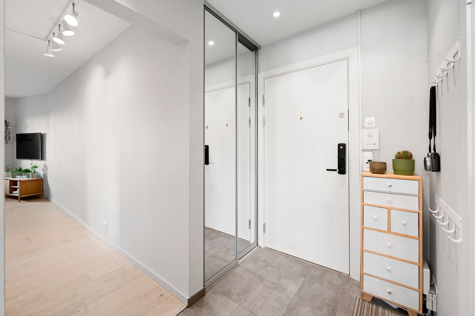Velkommen inn! Leilighetens entré er lys og innbydende og gir et godt førsteinntrykk av boligen. Det er gode oppbevaringsmuligheter i en praktisk skyvedørsgarderobe med speilfronter. Galleribilde