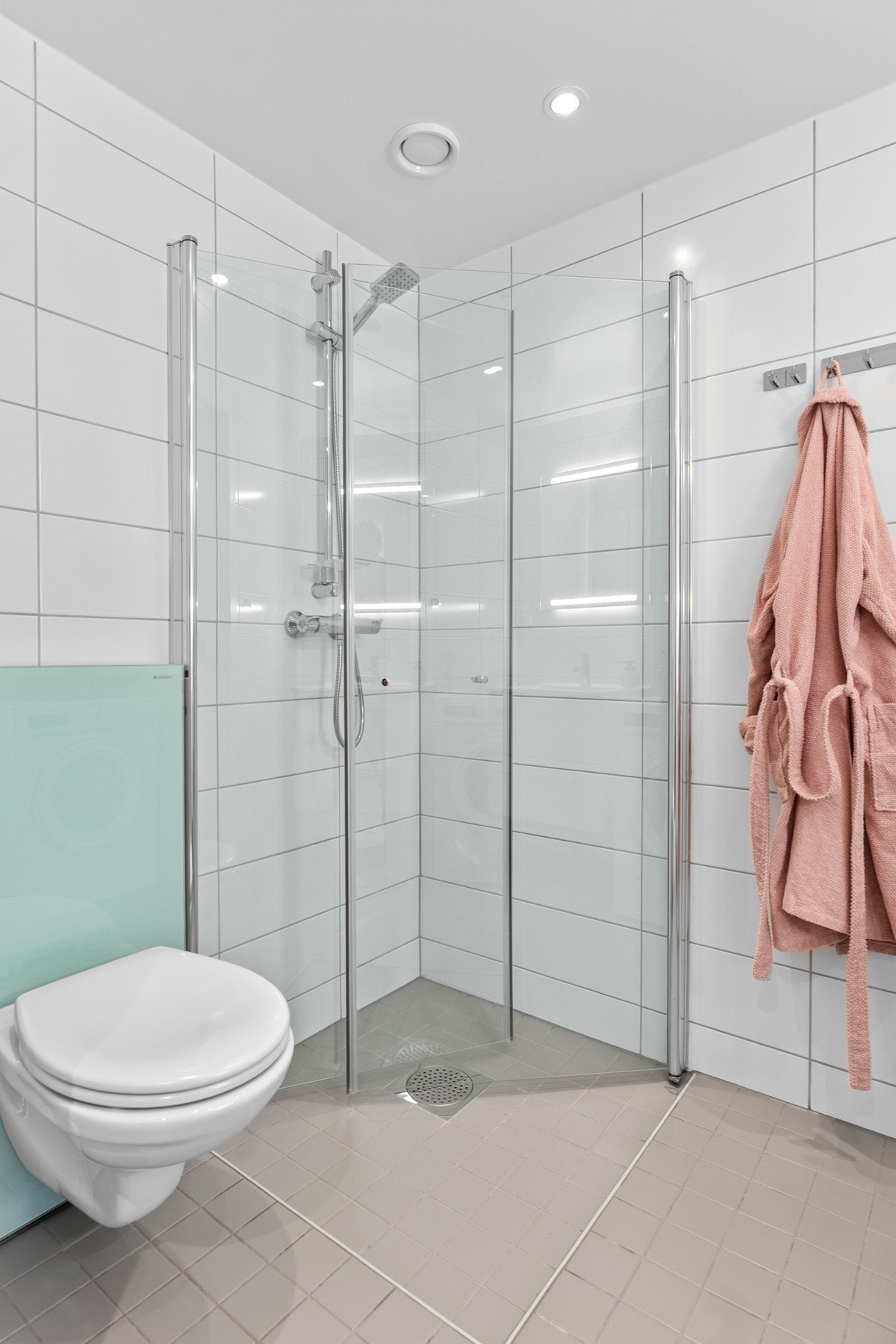 I hjørnet har du et dusjhjørne med rette svingdører i glass, sluk i sone og krom dusjutstyr samt vegghengt wc med sisterne i frostet glass. Galleribilde