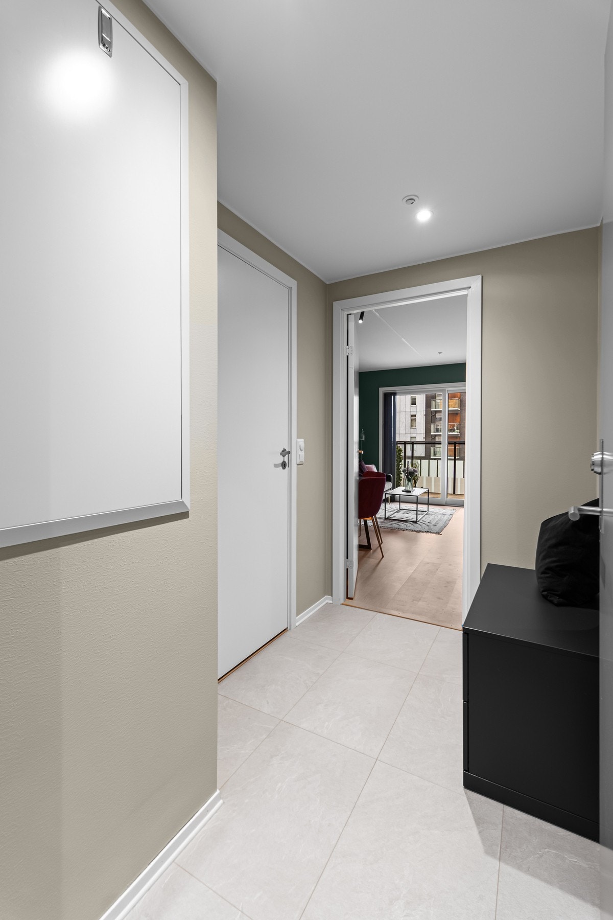 Flott entré med downlights i himling, lyse laminatfliser og glatte beigemalte overflater Galleribilde