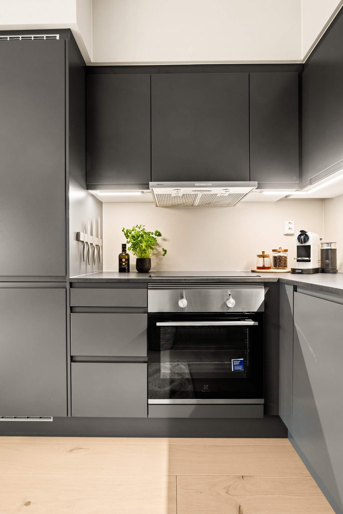 Stilrent og delikat kjøkken med mørke glatte fronter og benkeplate av laminat med nedfelt kum og koketopp. Galleribilde