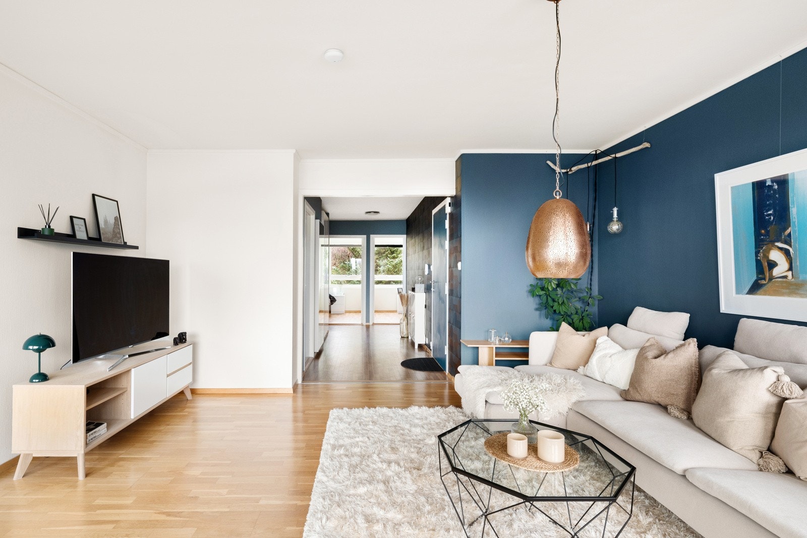 Stuegulvet har parkett, mens veggene er malt i hvitt og en mørk, tidsriktig blåtone. Rommet innredes enkelt med en stor sofagruppe, og innbyr til hygge fra tidlig morgen til sent på kveld. Galleribilde
