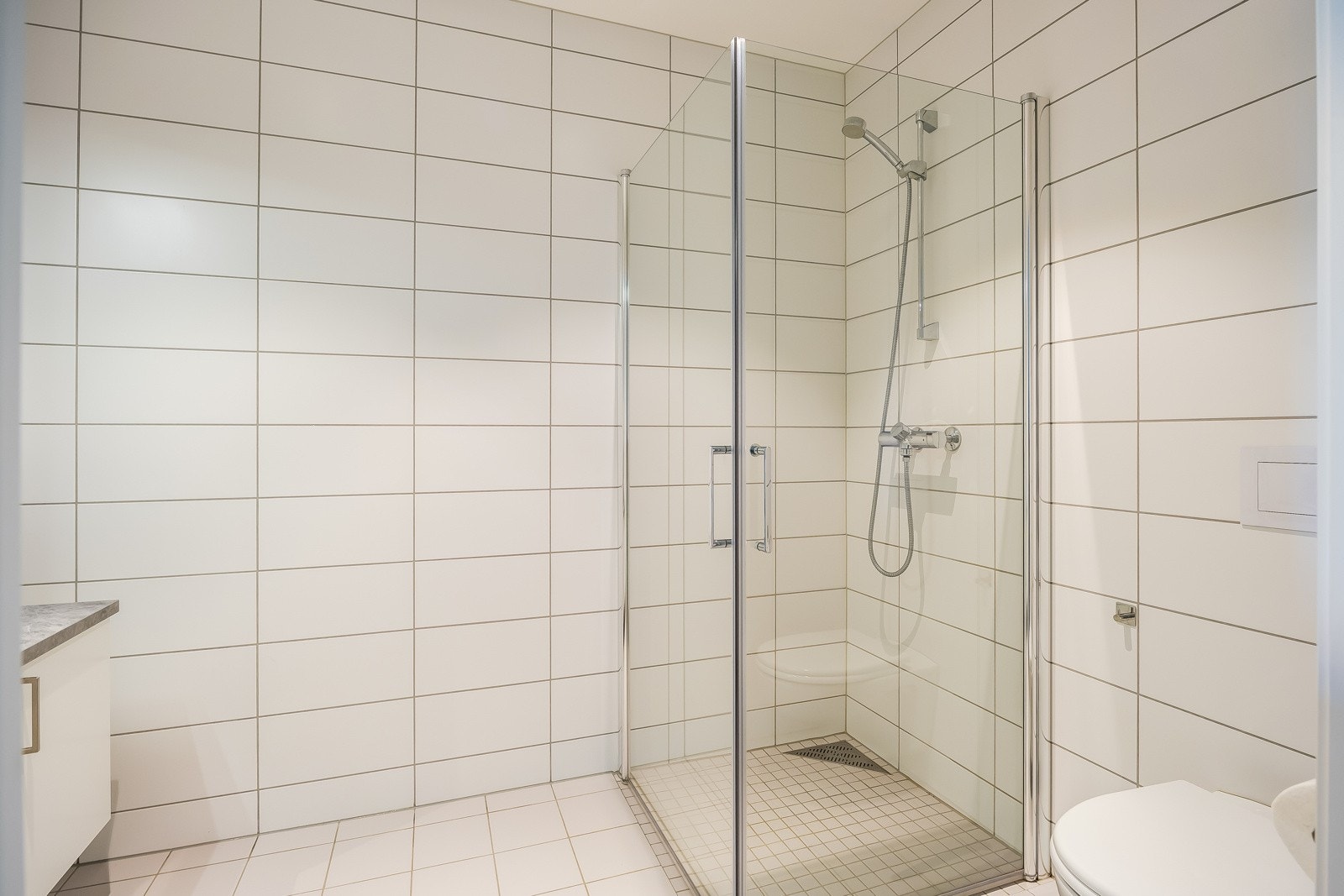 Badet har innfelbare dusjdører som frigjør gulvplass. Tilstandsgrad 1 iht. takstrapport. Galleribilde