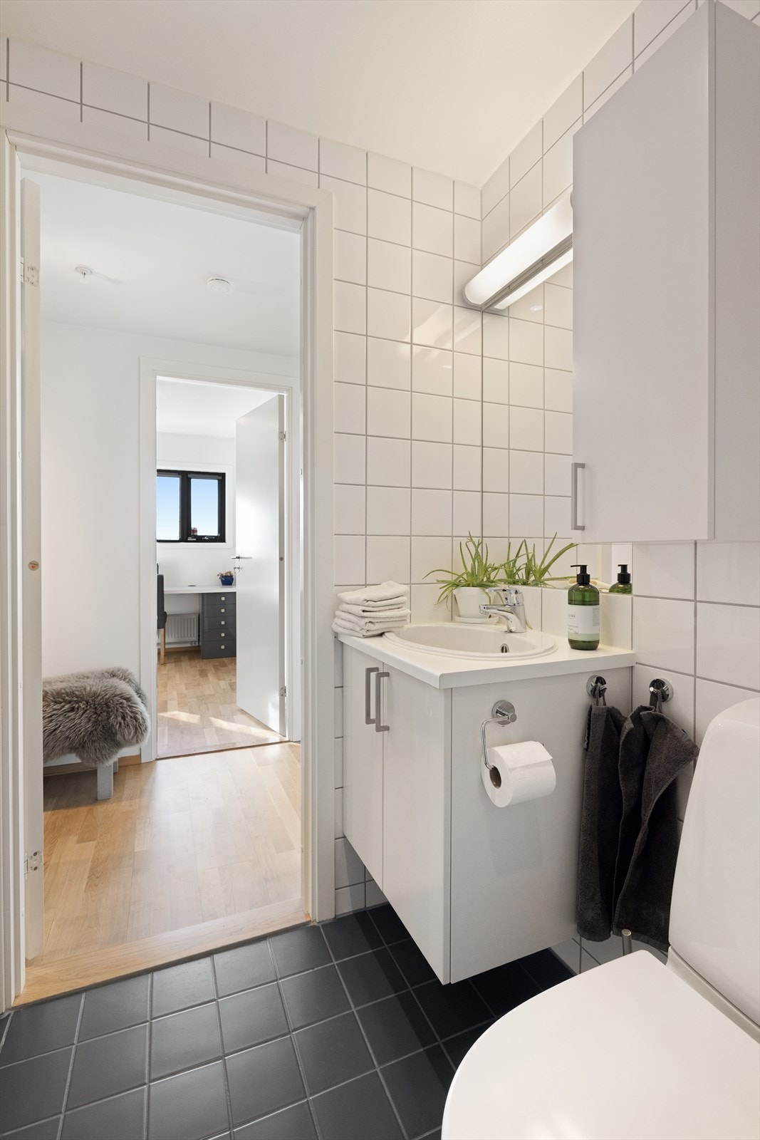 Badet er innredet med dusjhjørne med glassdører, servant i innredning med skap, speil med belysning, vegghengt skap og toalett Galleribilde