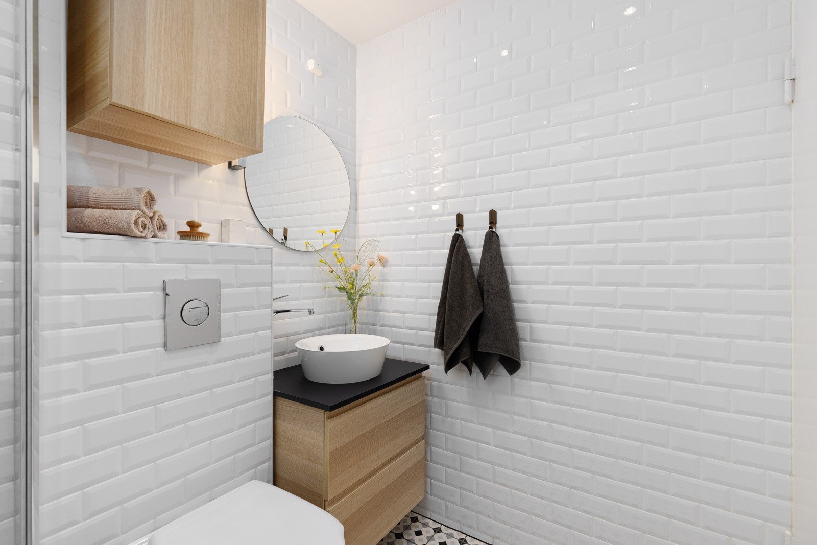 Det er veggfestet toalett, servant med benkeskap, veggskap med glatte fronter og speil over servanten. Galleribilde