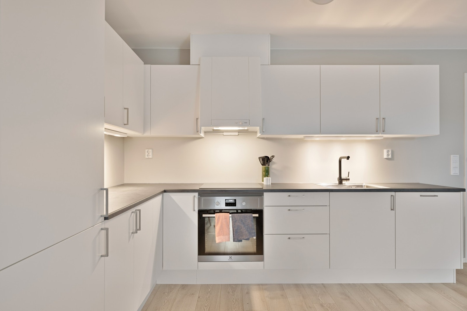 Pent og tidløst kjøkken med slette fronter, benkeplate i laminat og integrerte hvitevarer. Galleribilde