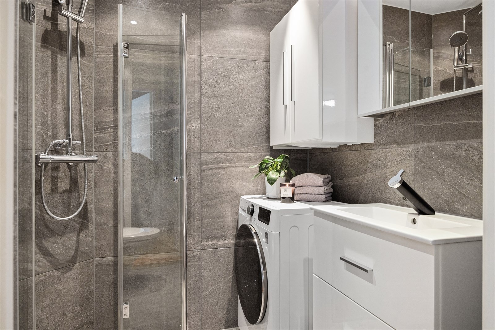 Innredet med servantskap med nedfelt servant, veggskap med speildører og vegghengt klosett med innebygd sisterne. Dusjsonen har innfelte dusjdører i herdet glass. Galleribilde