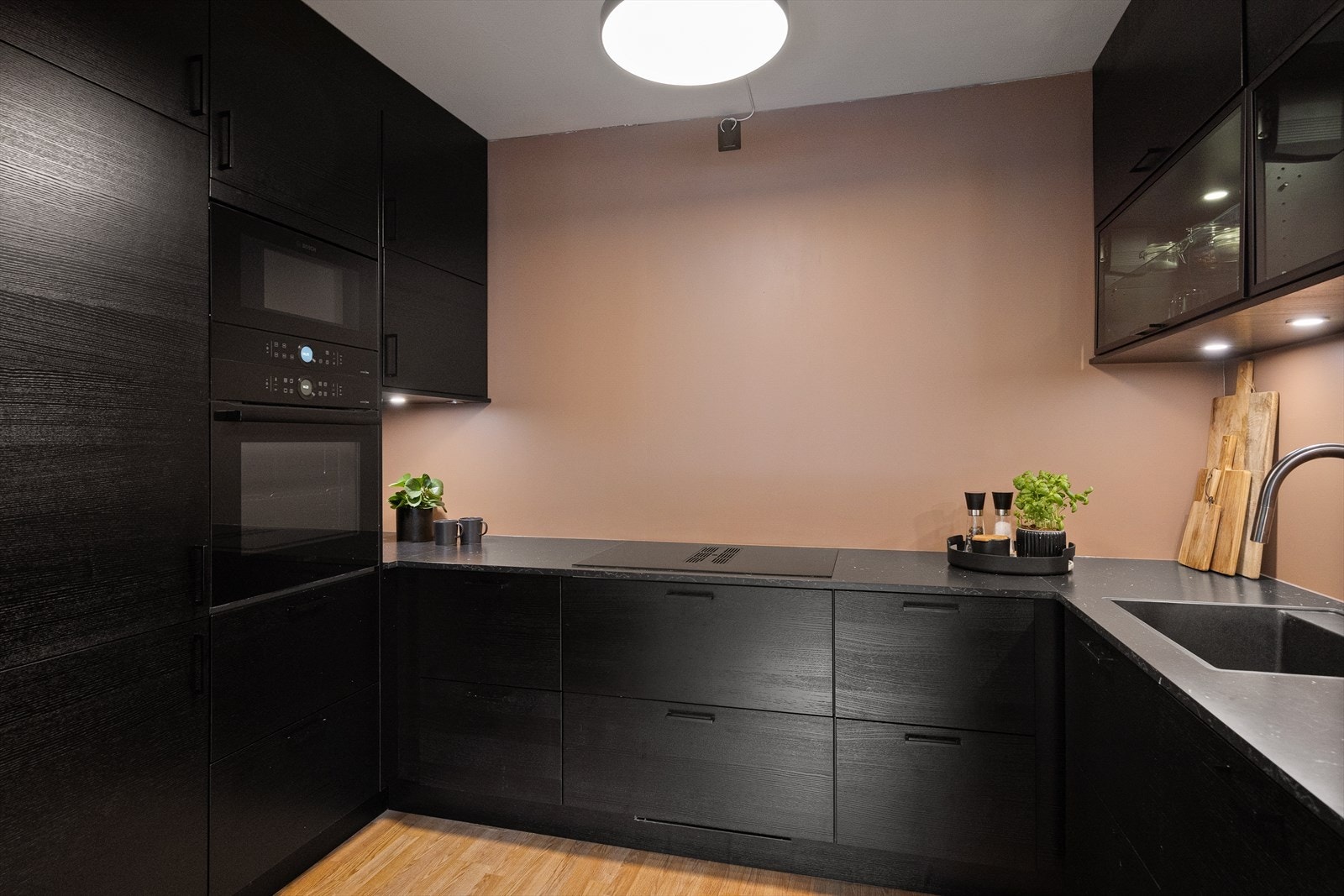 De sorte, glatte frontene gir et stilrent uttrykk, mens laminatbenkeplaten har en nedfelt oppvaskkum med ettgreps svingbart blandebatteri med dusj. Innredningen inkluderer både over- og underskap med belysning under overskap. Galleribilde