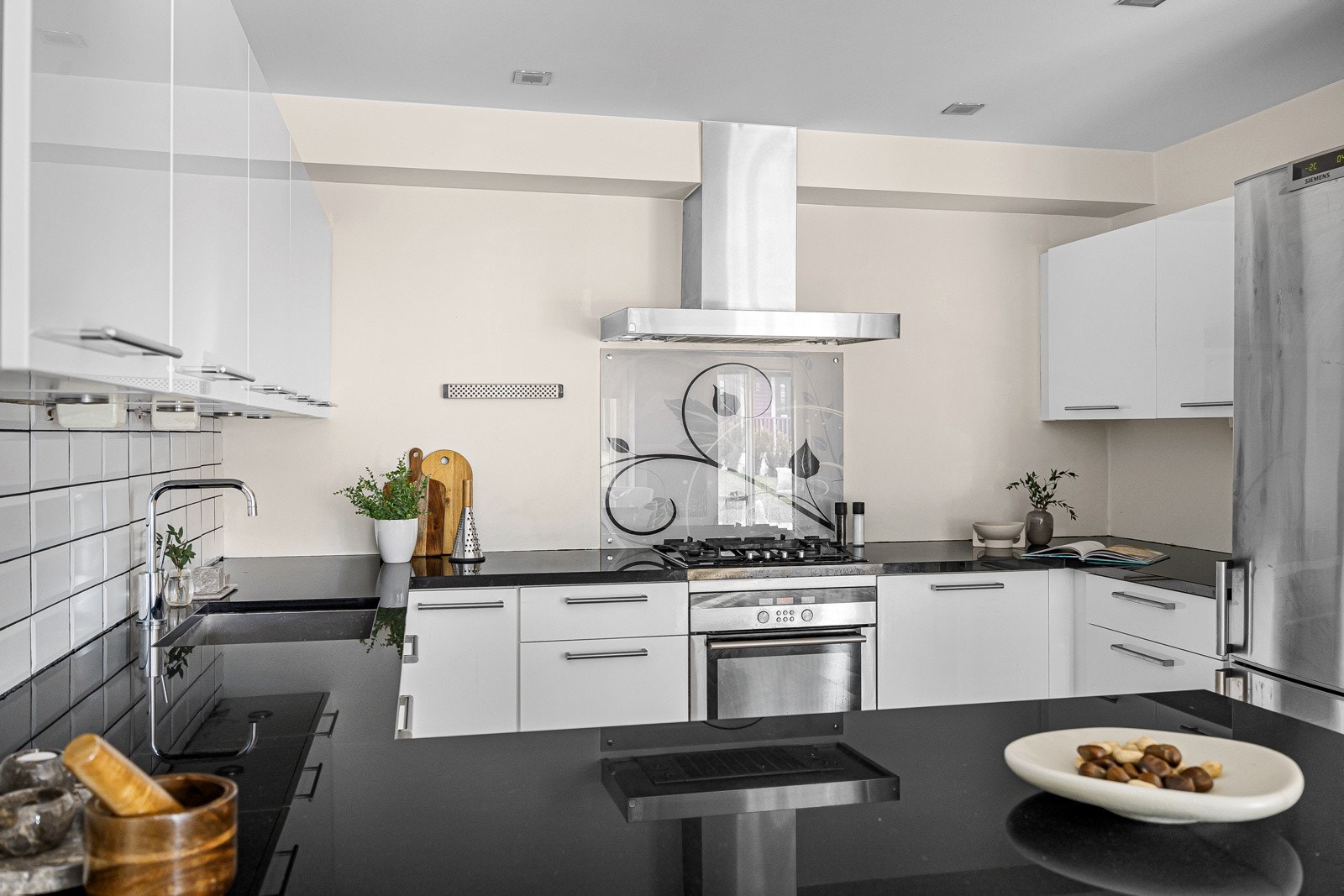 Lyst og romslig kjøkken med halvøy som deler kjøkkenet fra stuen. Galleribilde