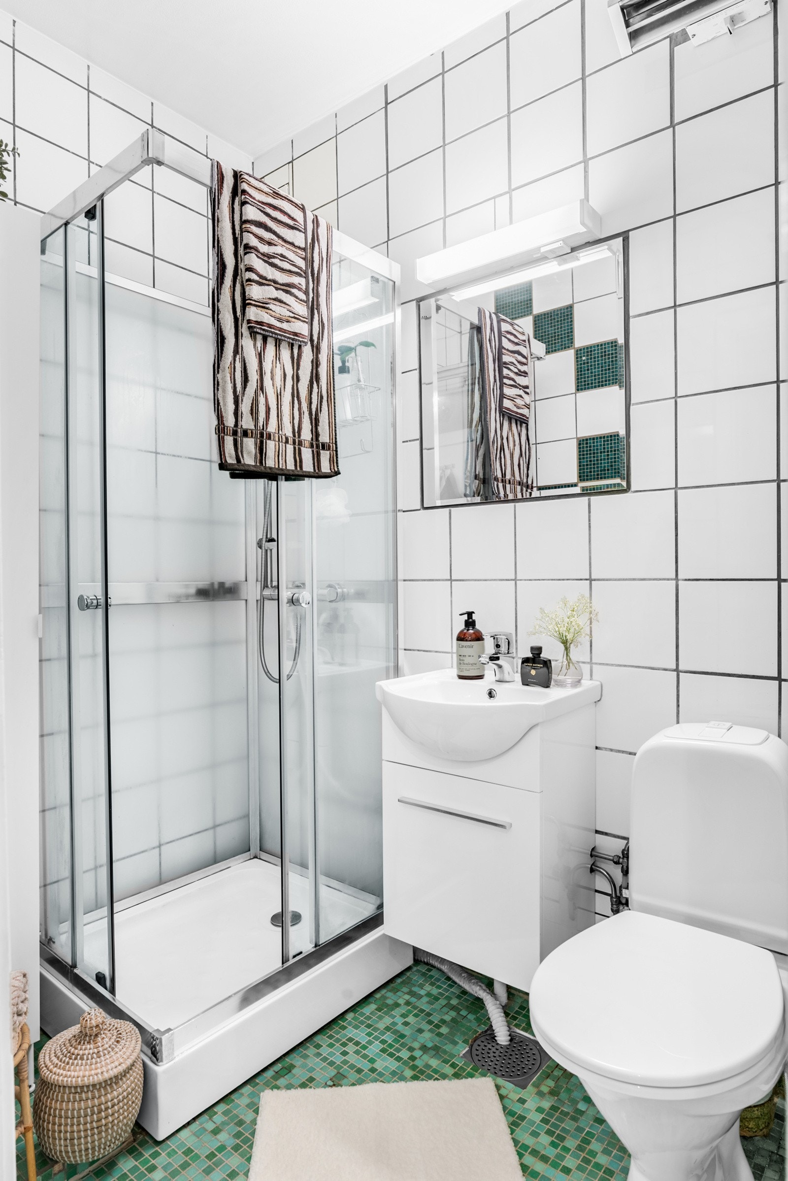 Flislagt bad innredet med dusjkabinett, toalett, servant og speil. Galleribilde