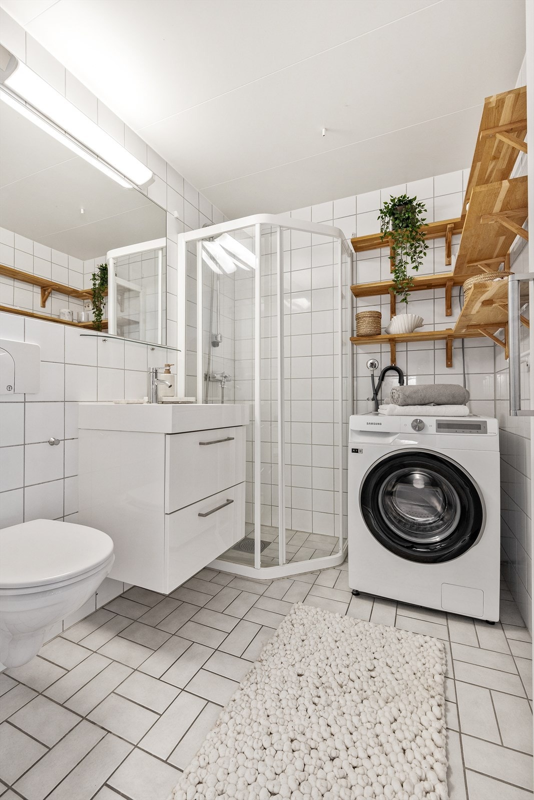 Innredningen består av veggfestet toalett med innebygget sisterne, dusjhjørne med skyvbar dør, servant med underskap, innmurt speil og eikehyller. Det er opplegg for vaskemaskin på badet. Galleribilde