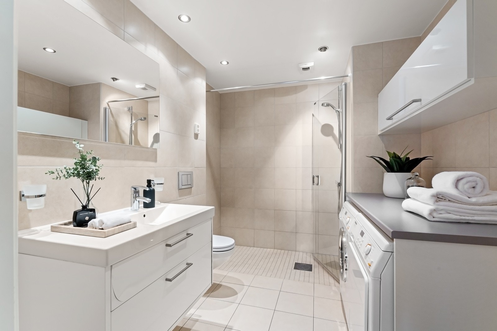 Delikat baderom i suiteløsning med hovedsoverommet. Badet har varme i gulvene, romslig dusjplass og en praktisk arbeidsbenk med nisje for vaskemaskin og tørketrommel. Galleribilde