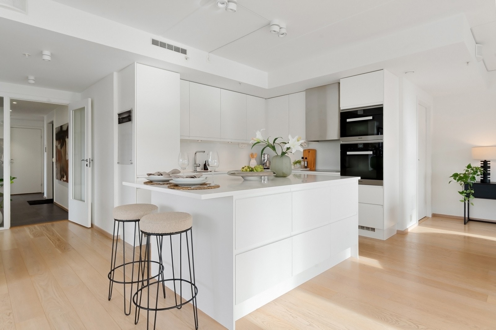 Kjøkkeninnredningen er eksklusiv og har glatte fronter med gripekant, kombinert med matchende benkeplate i Corian og glassplater som backsplash. Galleribilde