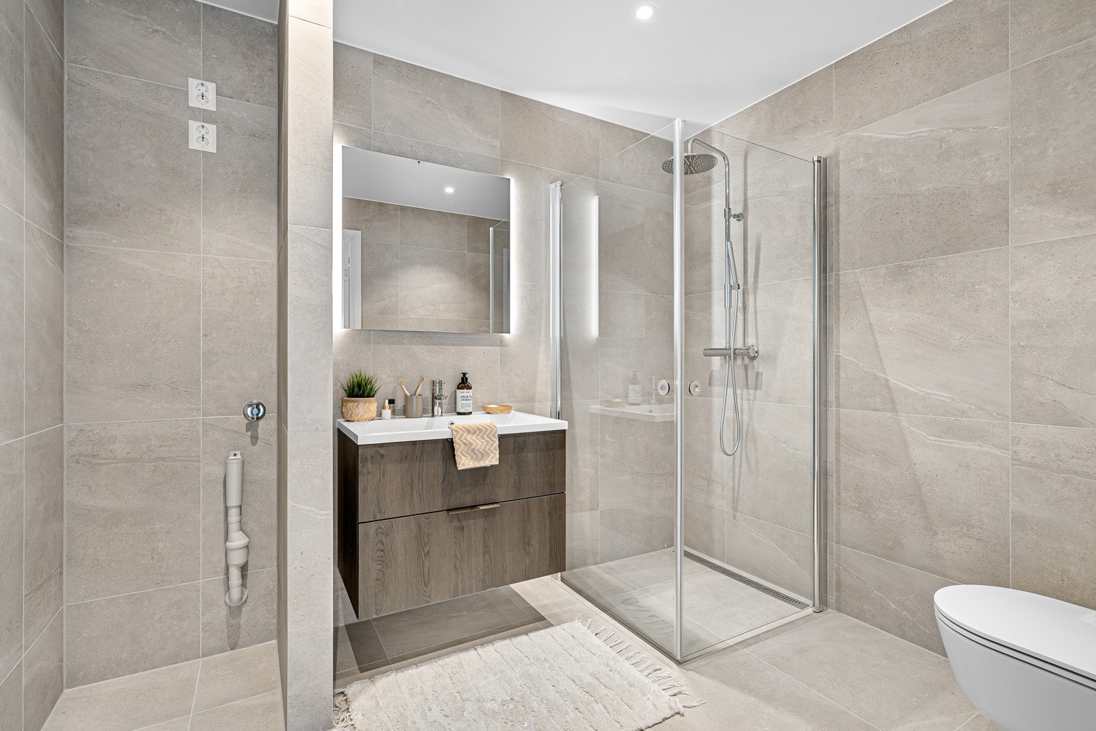 Badene er stilrene med delikate materialvalg og en moderne finish, der både gulv og vegger er kledd med store, duse fliser. Galleribilde