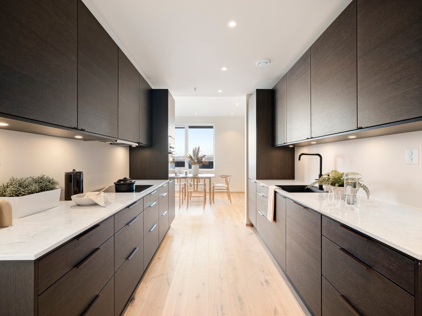 Innredningen av typen Amfi Kongle har glatte fronter i eik og sort oppvaskkum nedfelt i en lekker benkeplate av kompositt. Galleribilde