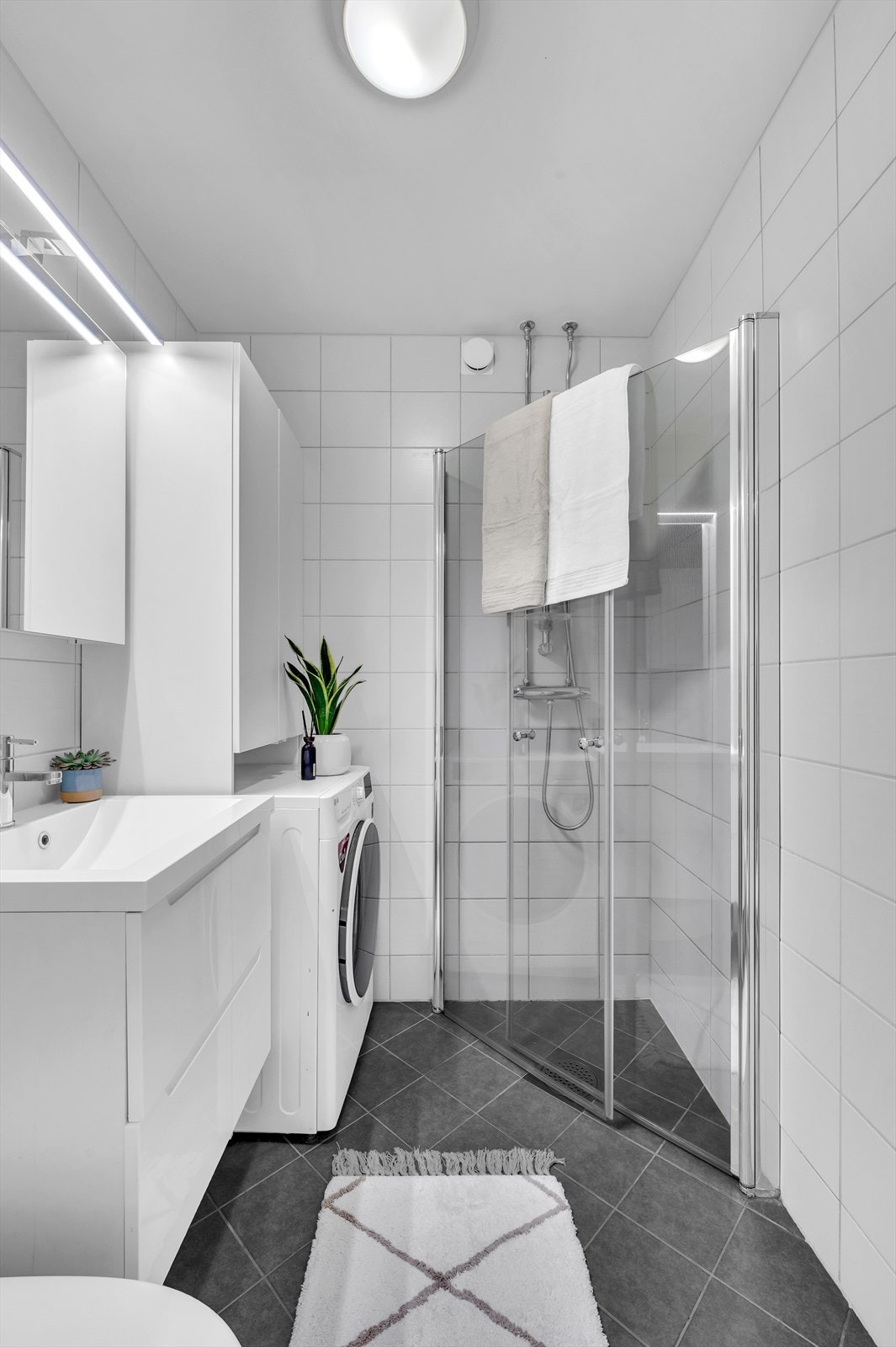 Baderommet er innredet med nedfelt servant, veggmontert toalett, dusjvegger/hjørne og opplegg for vaskemaskin. Badet har oppdriftsventil i dusjsone og tilluftsspalte under dør. Galleribilde