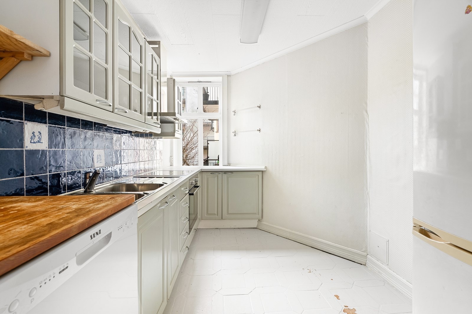 Eldre kjøkkeninnredning med folierte profilerte fronter og solid benkeplate med nedfelt dobbel vask. Galleribilde