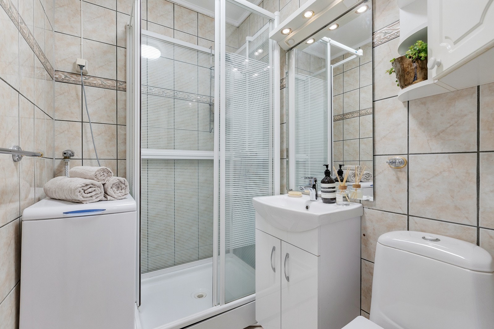 Flislagt baderom med vegghengt innredning med ovenpåliggende servant og toalett. Galleribilde