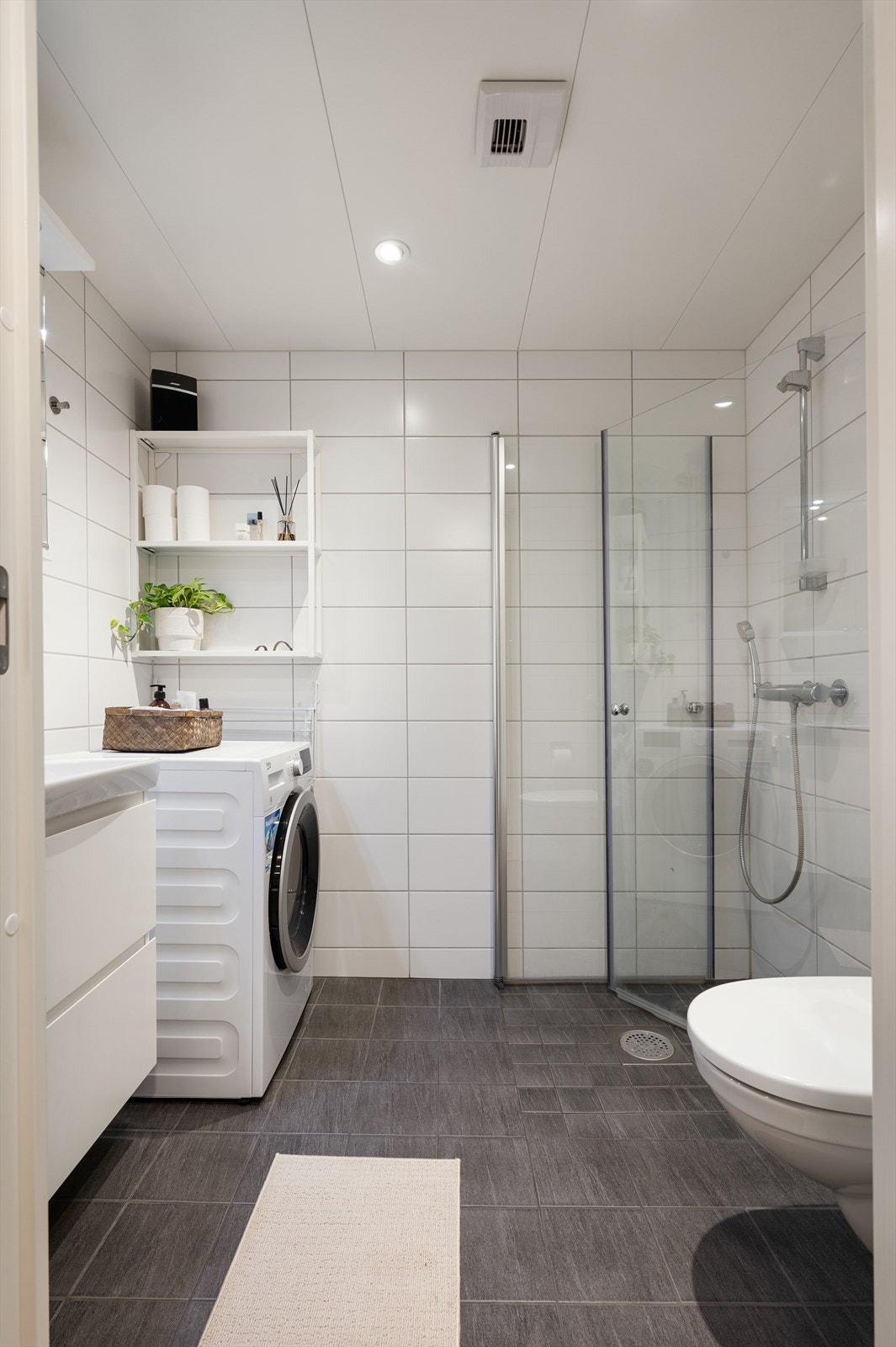 Innredningen består av et vegghengt klosett, en servant nedfelt i innredningen, og et dusjhjørne med svingbare glassdører. Opplegg for vaskemaskin. Galleribilde