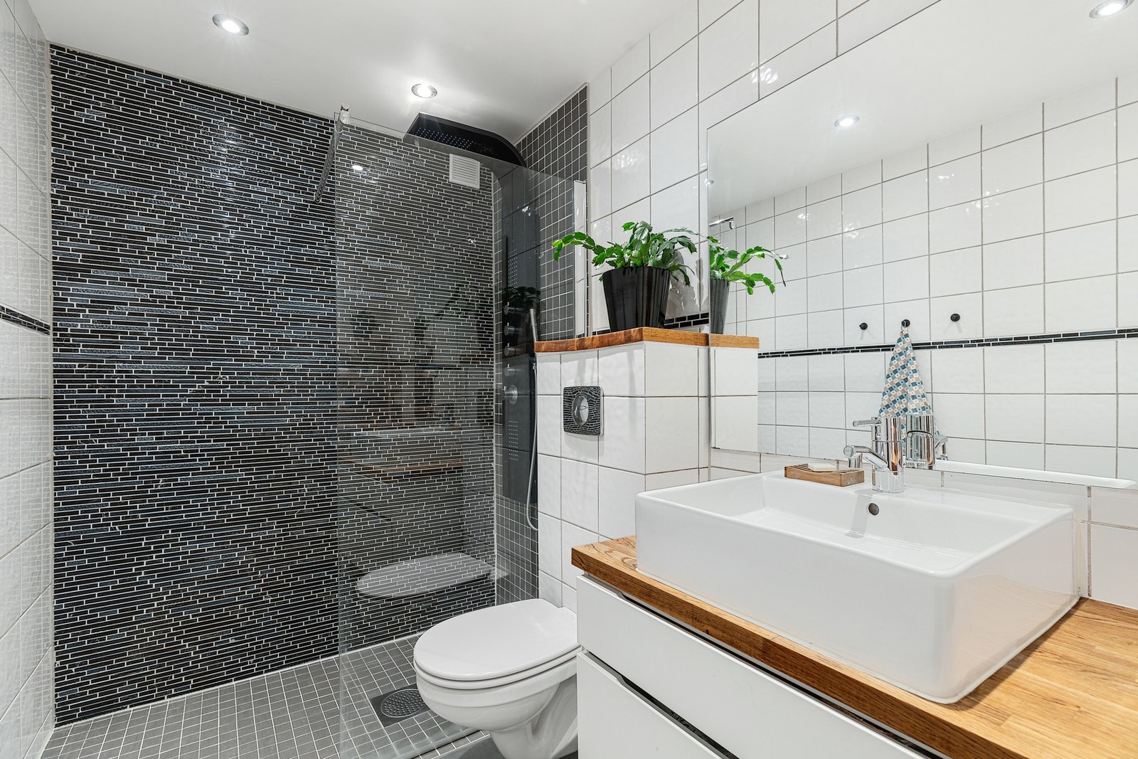 Badet er innredning med veggmontert toalett, toppmontert servant og dusjnisje med glassvegg. Galleribilde