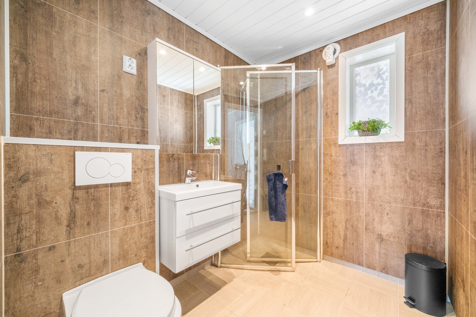 Bad i 1 etasje har fliser med varmekabler på gulv og baderomsplater på vegg. Galleribilde