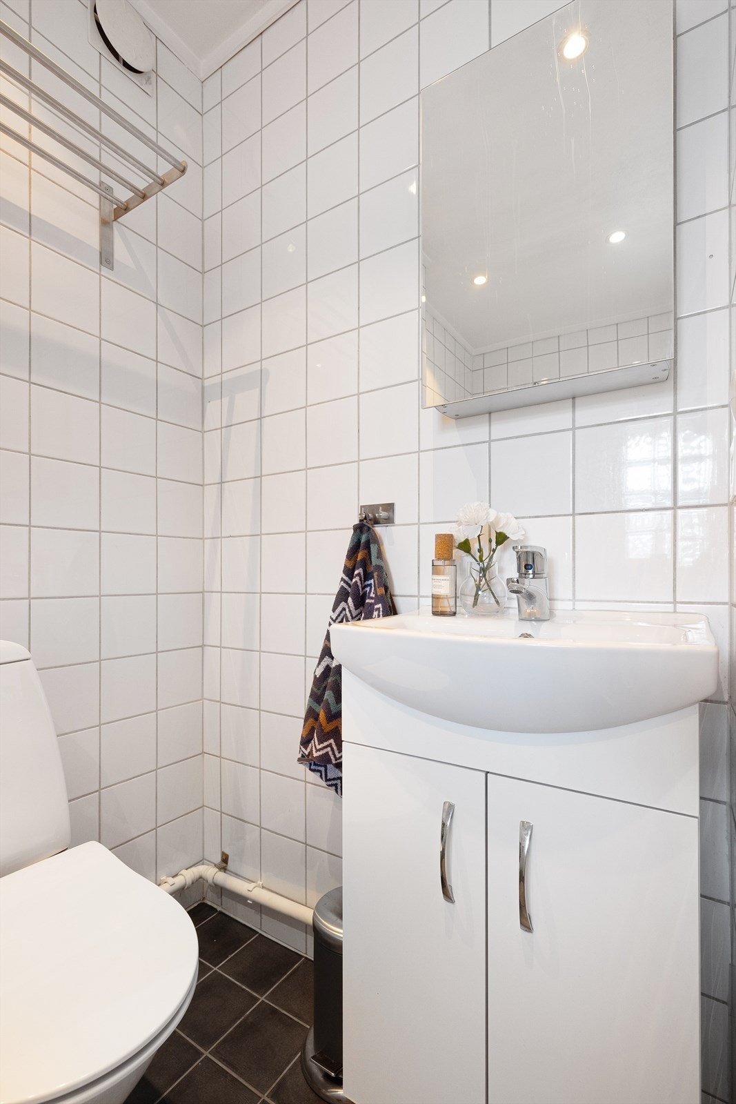 Badet er innredet med toalett, dusjhjørne med glassdør og baderomsinnredning med speilskap Galleribilde