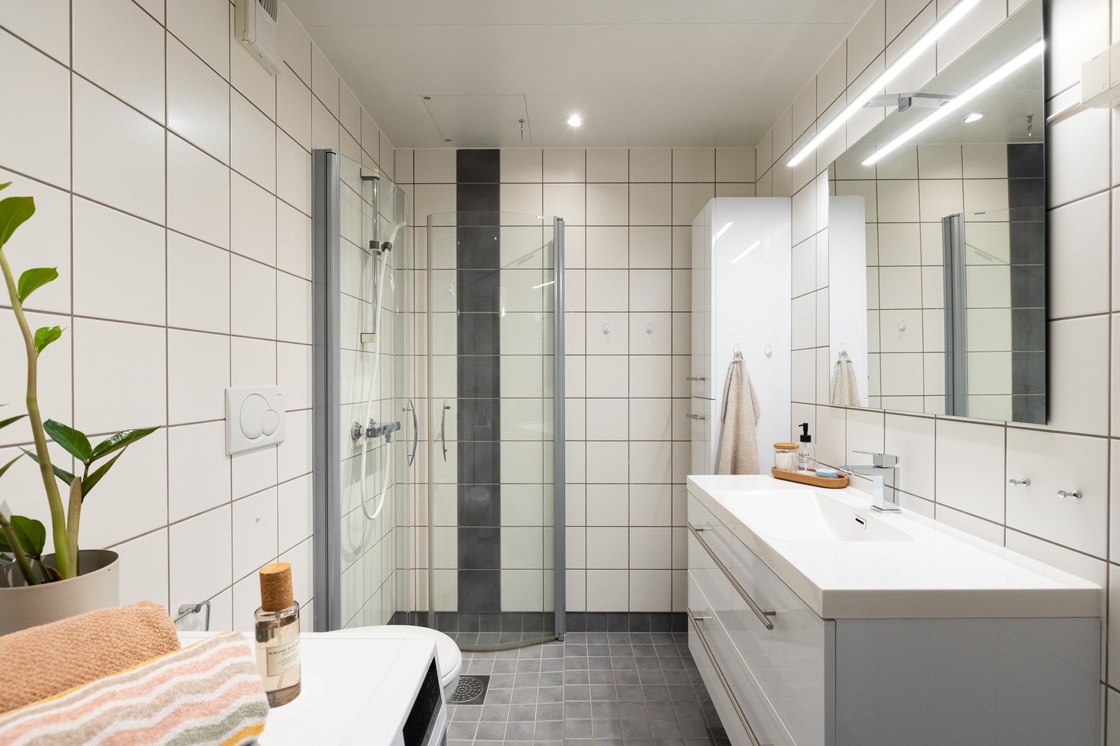 Badet er utstyrt med dusjhjørne, servant med underskuffer, speilskap og vegghengt toalett. Galleribilde