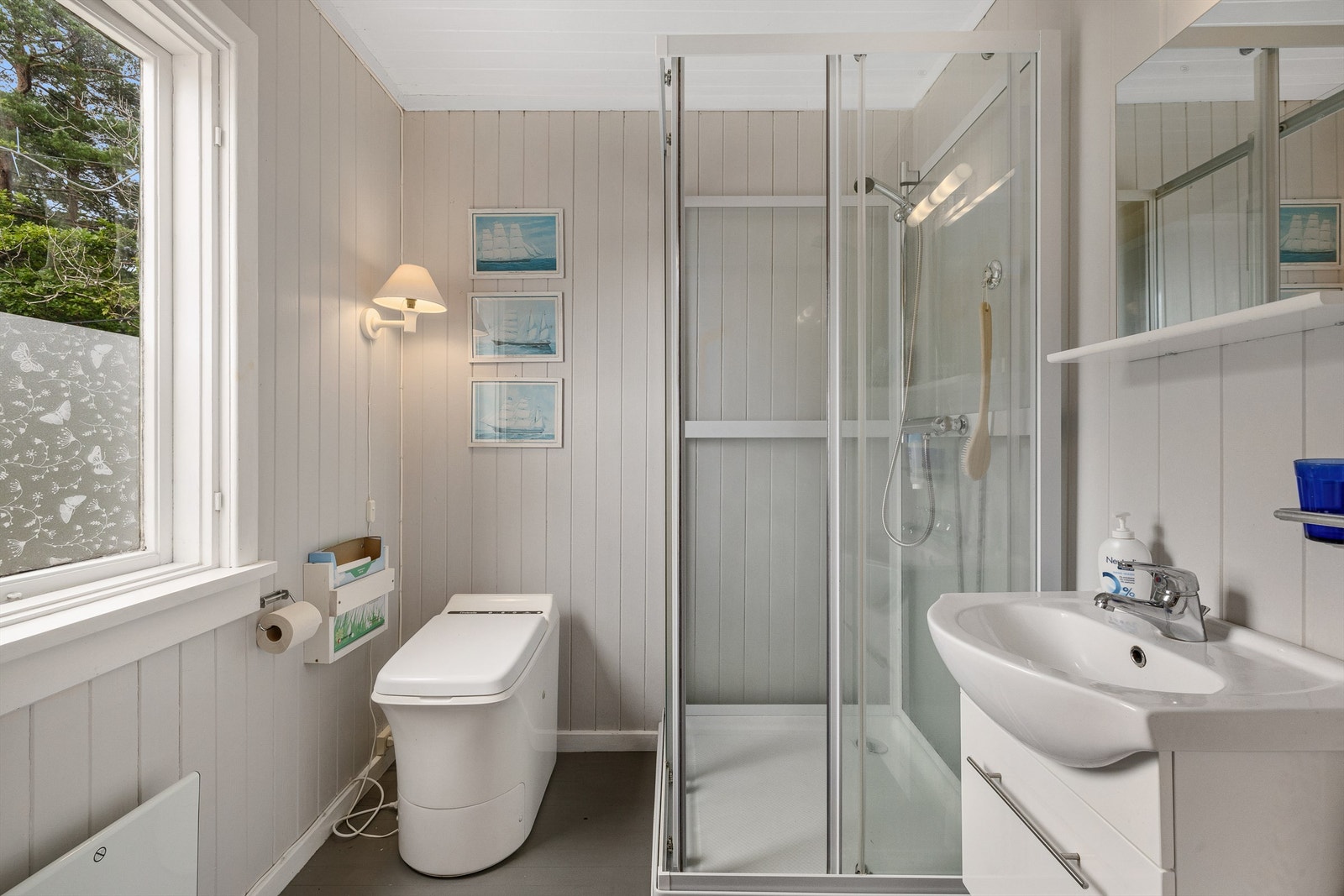 Badet er enkelt og praktisk , med forbrenningstoalett, dusjkabinett og vask med skuffeseksjon under. Galleribilde
