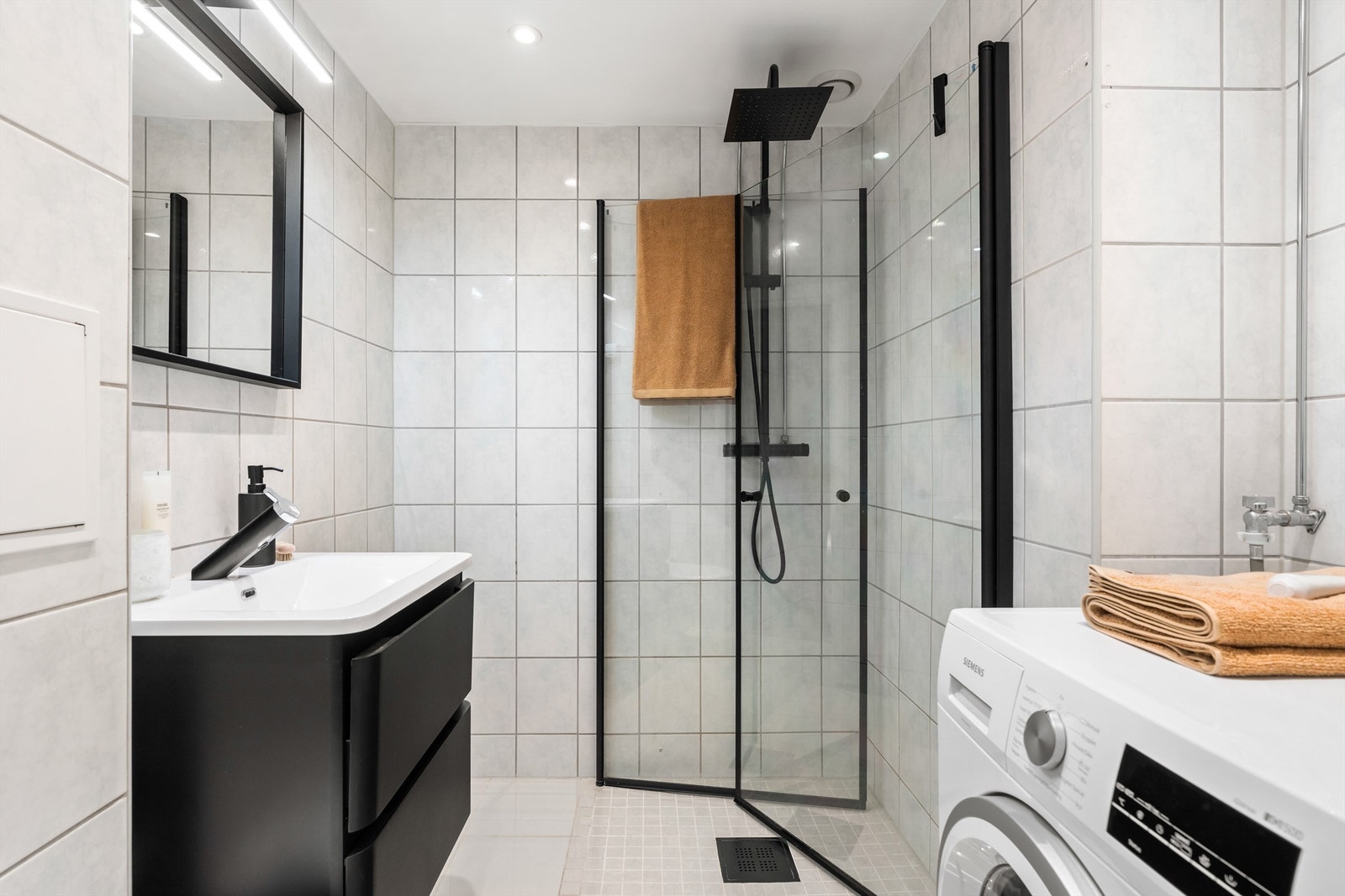 Tidløst og flislagt bad med gulvvarme, downlights i himling og opplegg til vaskemaskin. Galleribilde