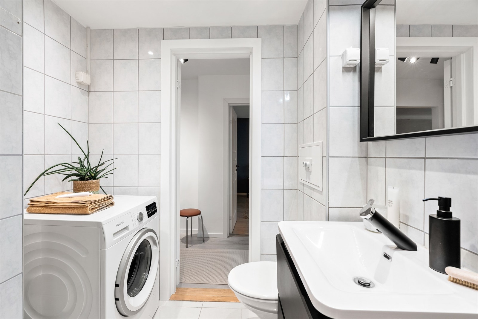 Innredningen består blant annet av vegghengt servantinnredning med skuffer og heldekkende servant. Speil med overbelysning på vegg over servanten. Videre har badet dusjhjørne med svingbare glassdører og vegghengt toalett. Galleribilde