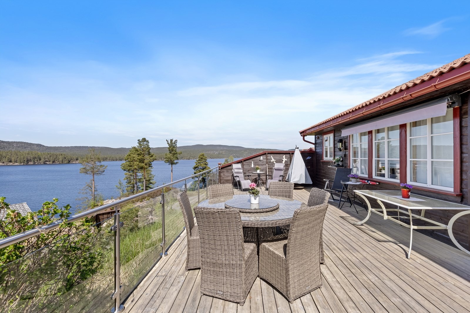 Romslig terrasse med glassrekkverk som ikke hindrer utsikten i front, skaper muligheter for trivelige dager og kvelder utendørs Galleribilde