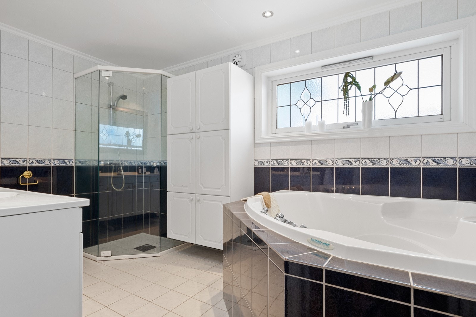 På badet er det både et dusjhjørne med skyvedører og et innfliset boblebadekar med liten trapp. Galleribilde