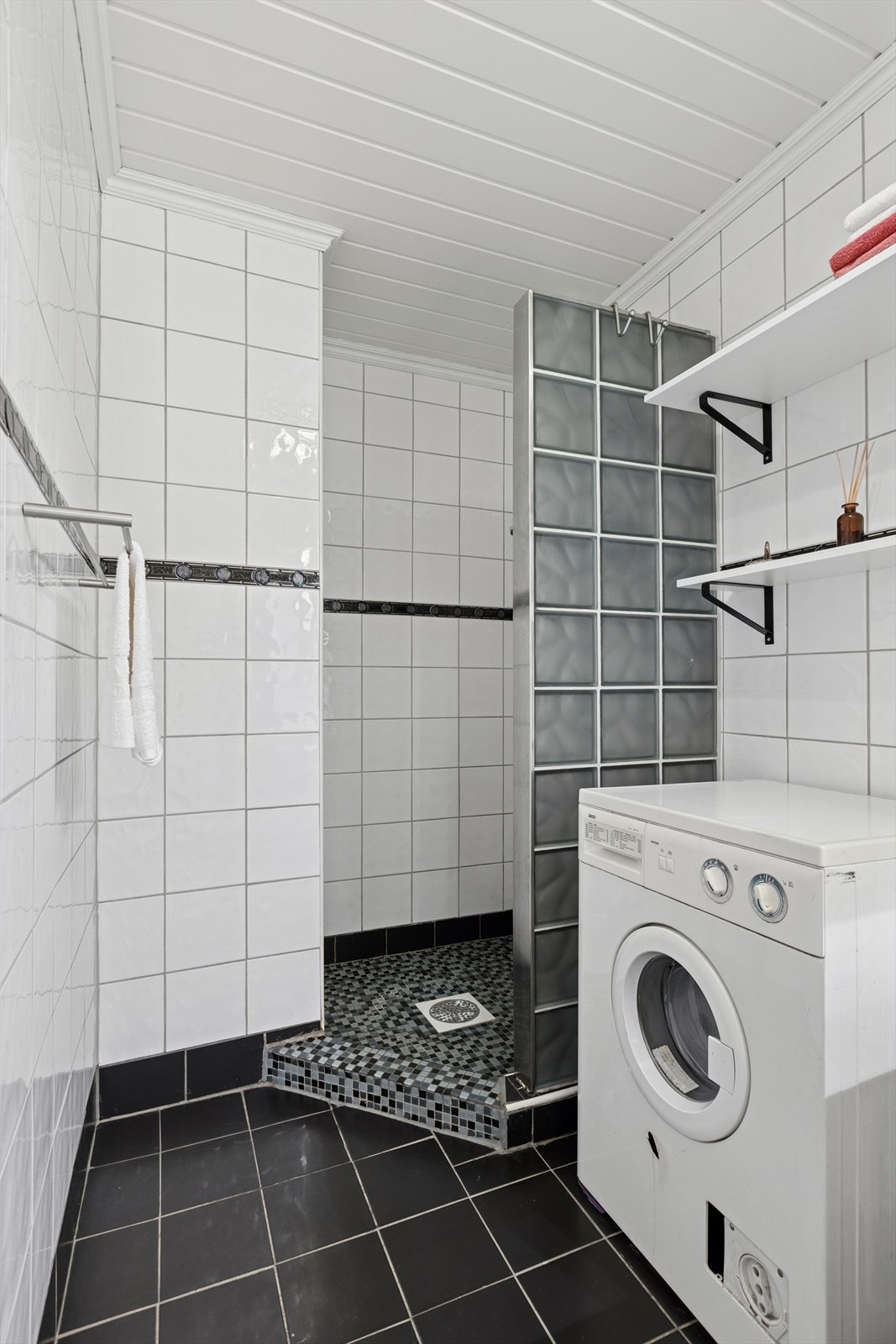 Badet er utstyrt med vegghengt toalett, servantinnredning, opplegg for vaskemaskin og dusjhjørne. Galleribilde