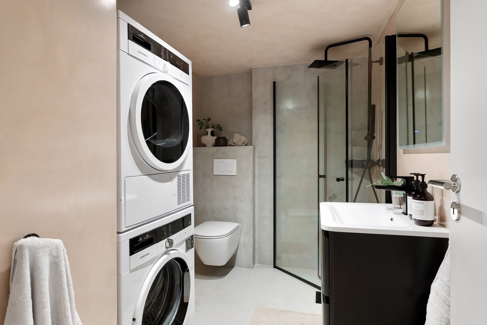 Delikat bad med regnfalldusj, glassdører, vegghengt toalett og servant med skuffer. Opplegg for vaskemaskin og tørketrommel. Galleribilde