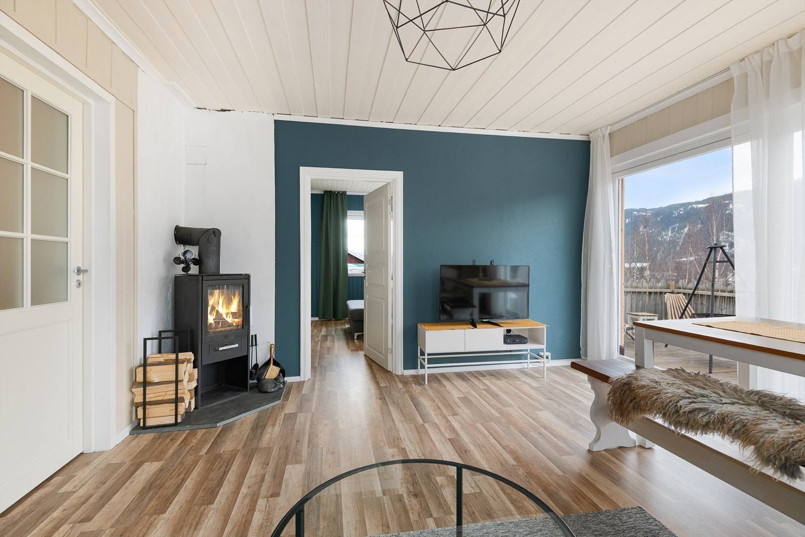 Lys og innbydende stue med moderne peis og store vinduer som gir flott utsikt til omkringliggende natur. Galleribilde