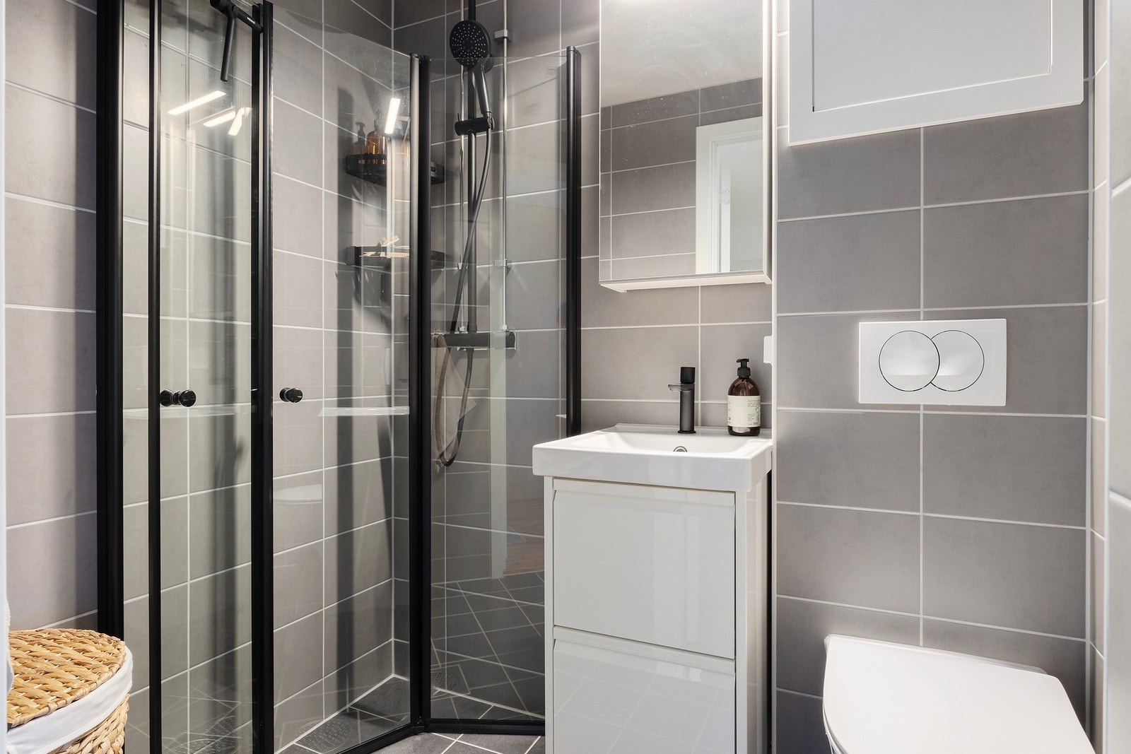 Badet er innredet med dusjhjørne med innfellbare glassdører, vegghengt wc, servantskap, speilskap på vegg, belysning og opplegg for vaskemaskin. Galleribilde