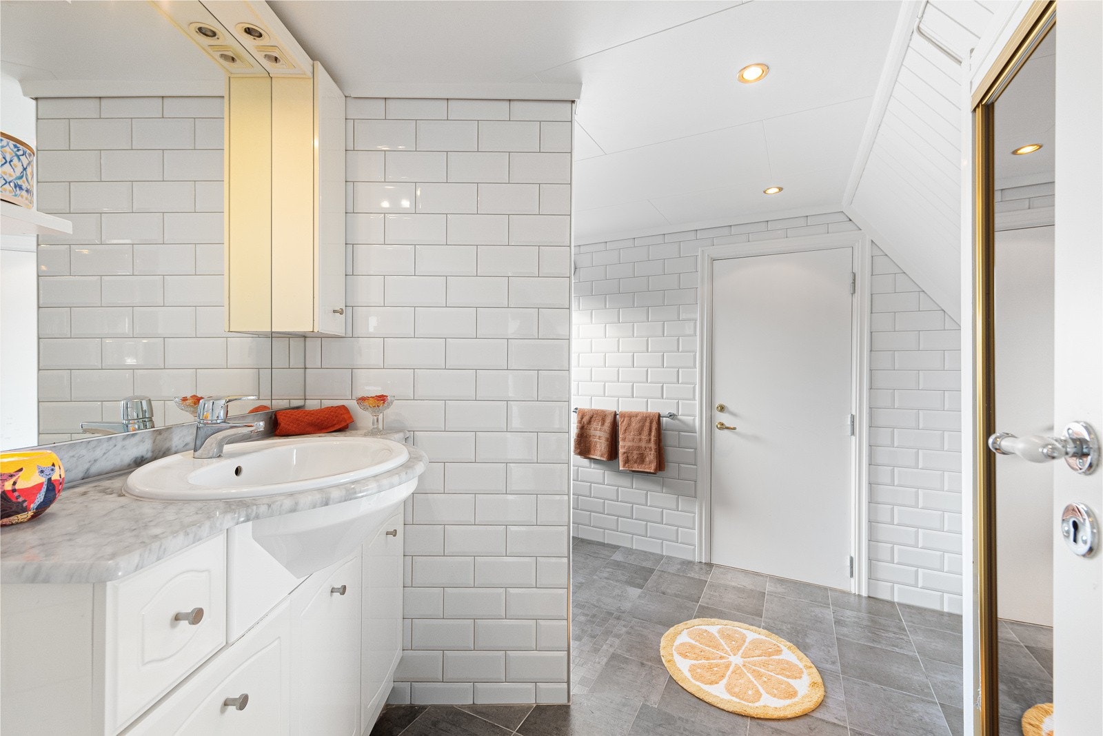 Det romslige baderommet i leiligheten er lyst og trivelig. Det ble delvis renovert i 2016. Rommet har innredning med nedfelt servant og speil. Galleribilde