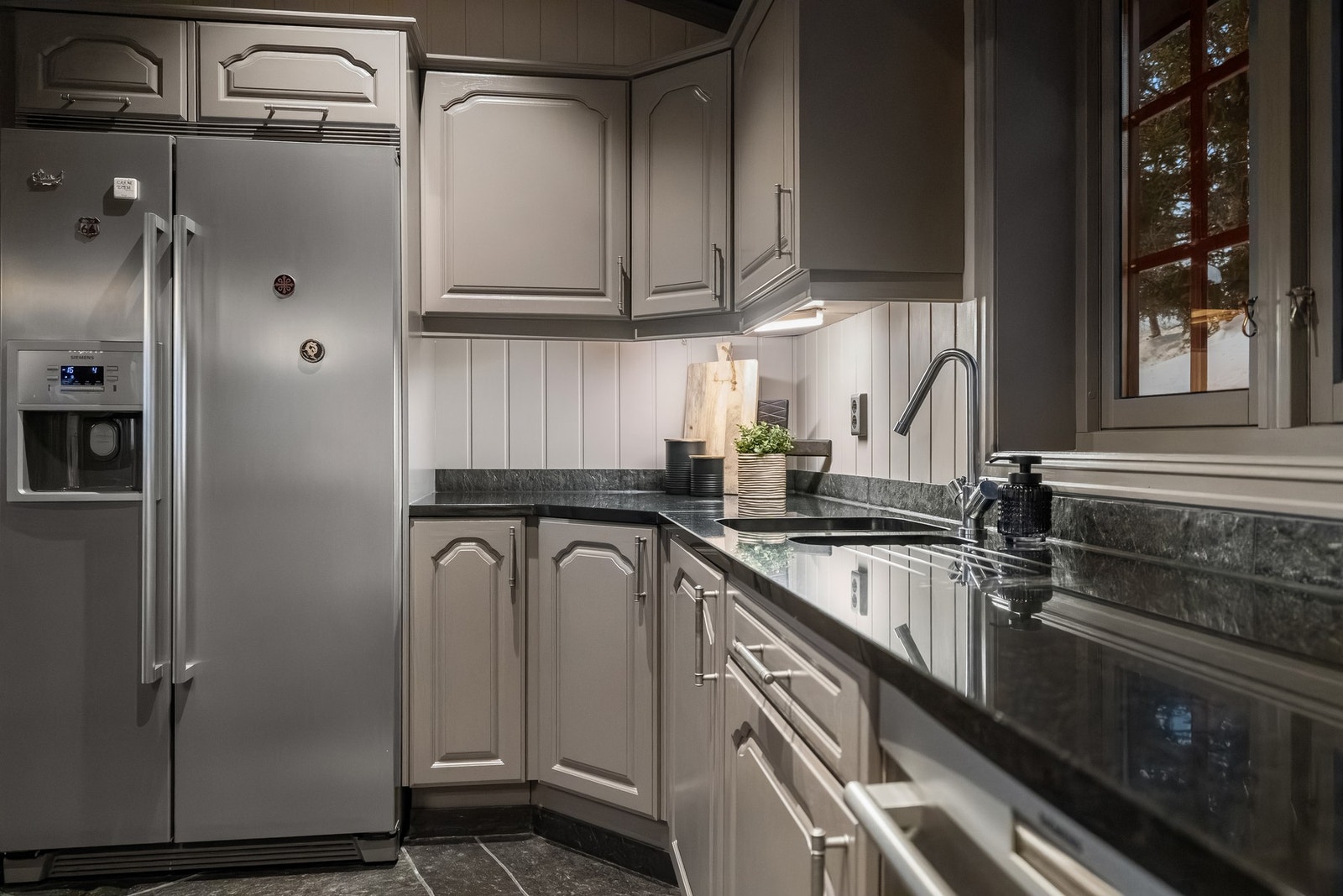 Kjøkkenet har flislagt gulv med varmekabler. Innholdsrik heltre innredning med malte profilerte fronter. Galleribilde