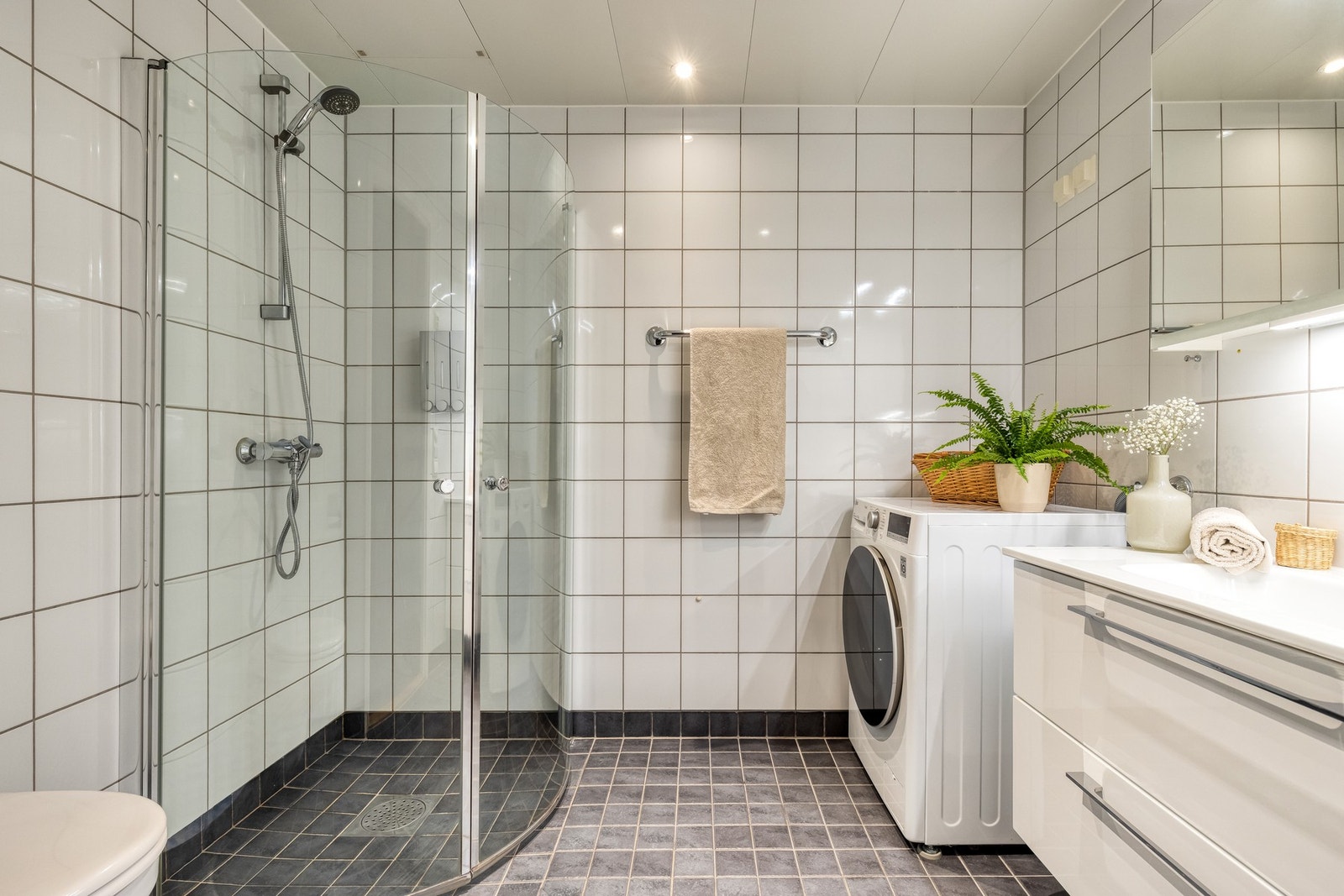 Stor bad med tidløse fliser på gulv og vegg. Badet har moderne fasiliteter som varme i gulv og downlights i taket. Galleribilde