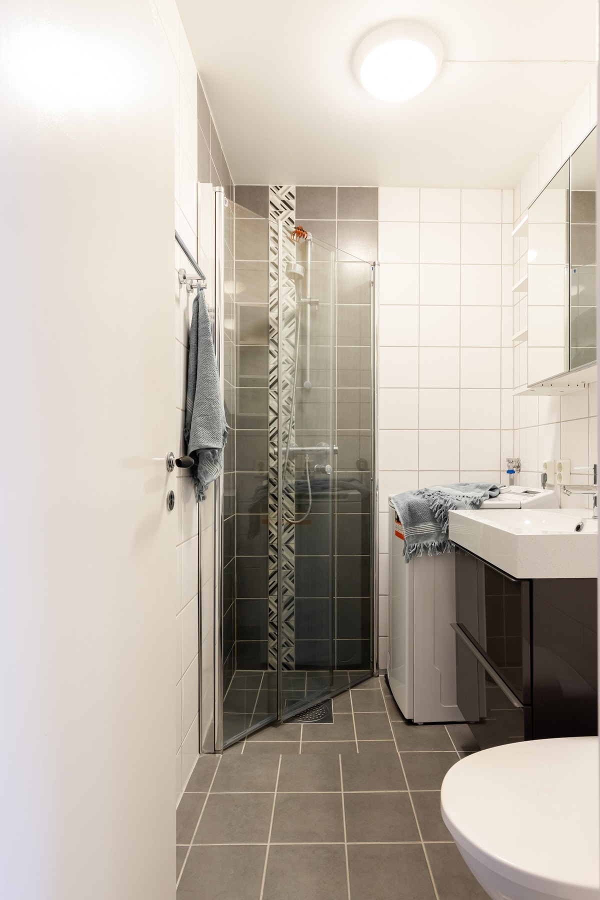 Badet inneholder dusjhjørne, innredning med skuffer, speilskap og vegghengt toalett. Varme i gulv. Galleribilde