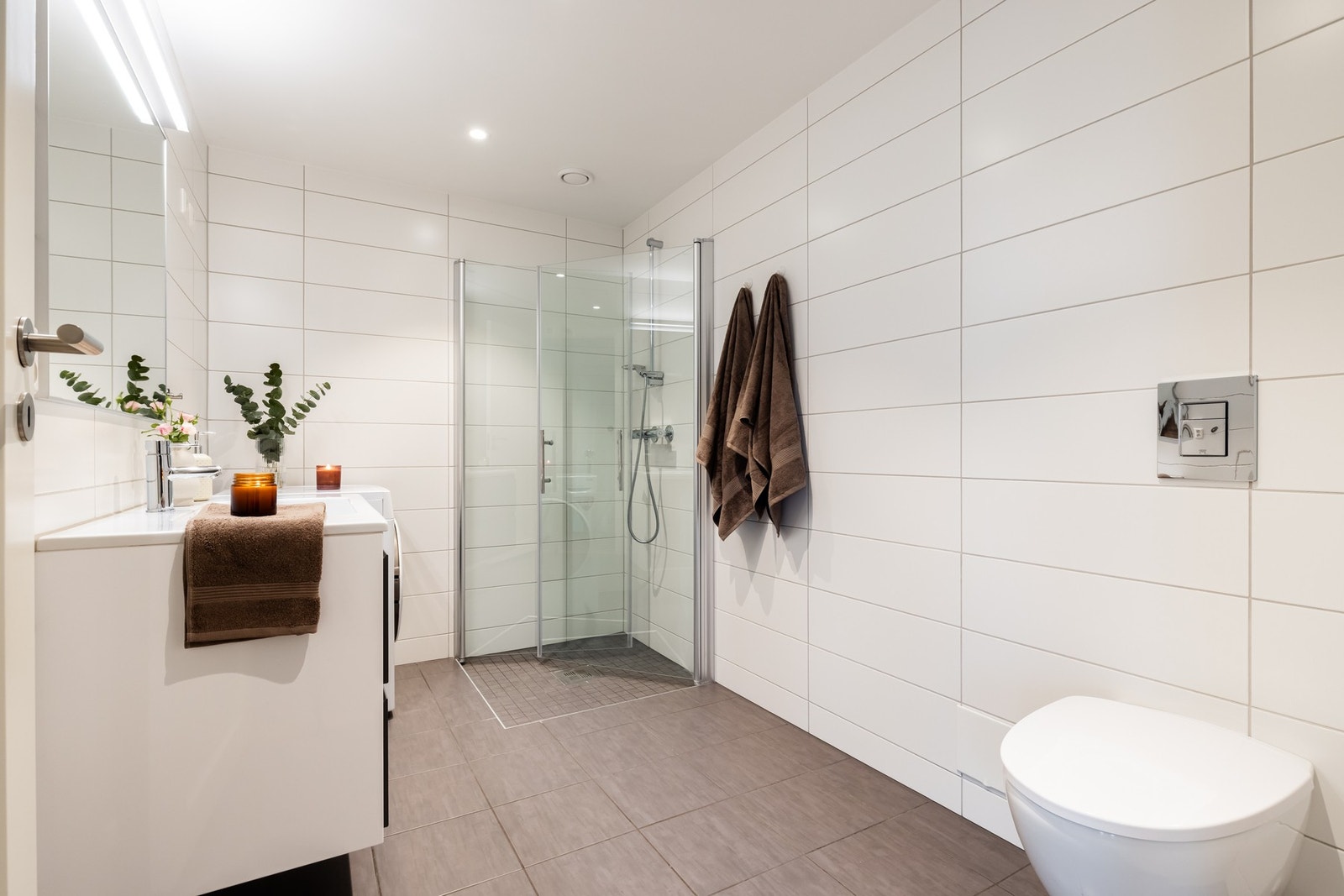 Videre er badet utstyrt med dusjhjørne med dusjvegger, vegghengt toalett og opplegg/plass til vaskemaskin og tørketrommel. Galleribilde