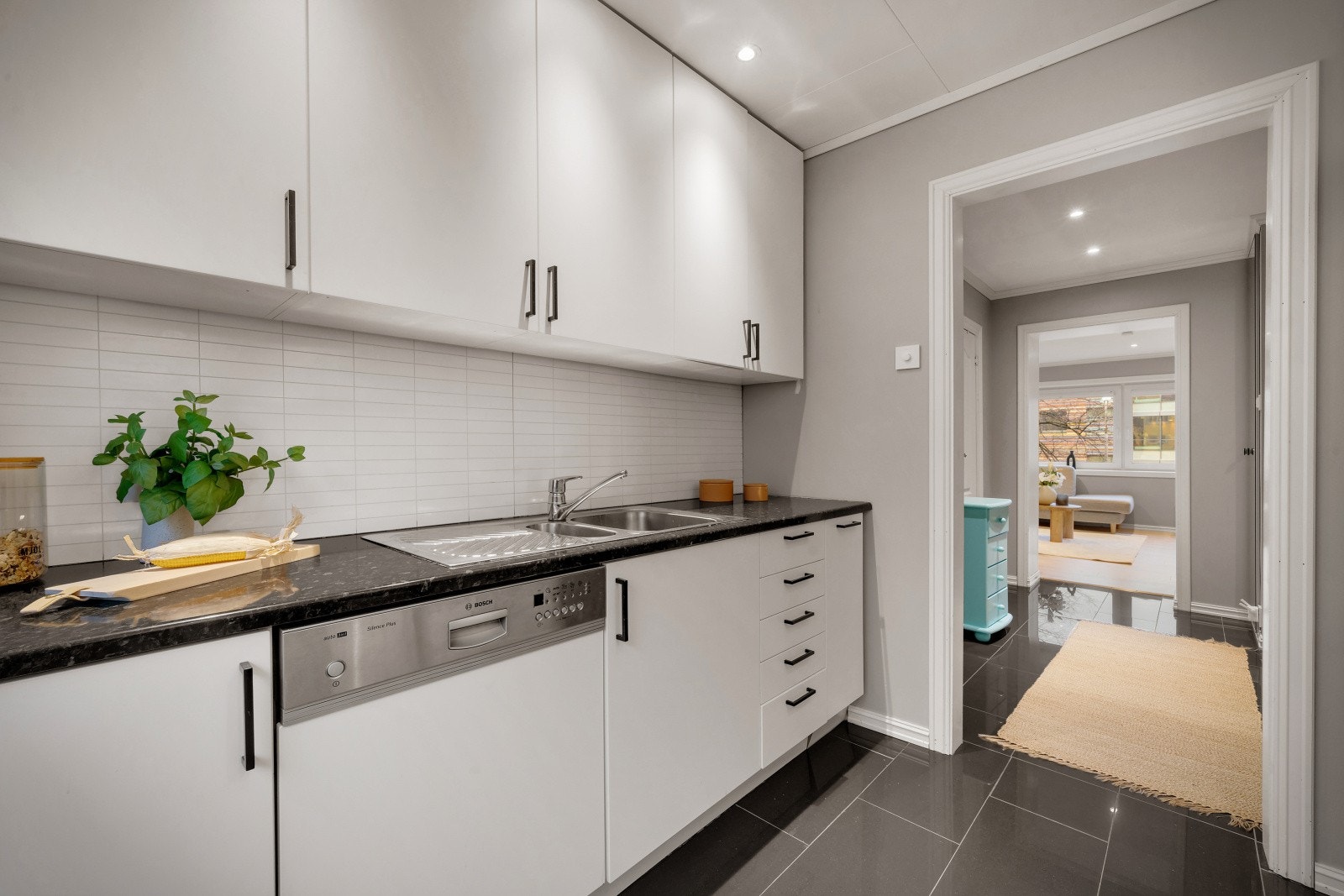 Kjøkkeninnredning med hvite glatte fronter og laminert benkeplate med planlimt kjøkkenbeslag. Galleribilde