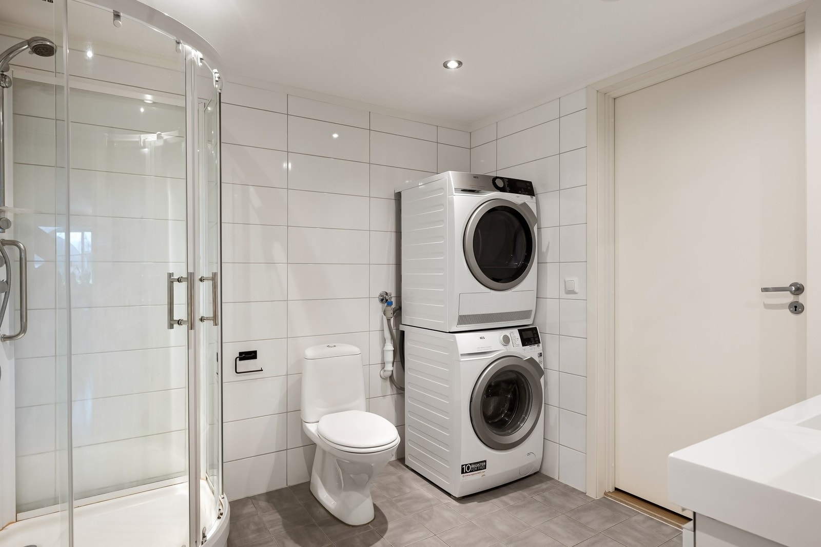 Rommet har innredning med servant, speilskap, toalett, dusjkabinett og opplegg for vaskemaskin. Galleribilde