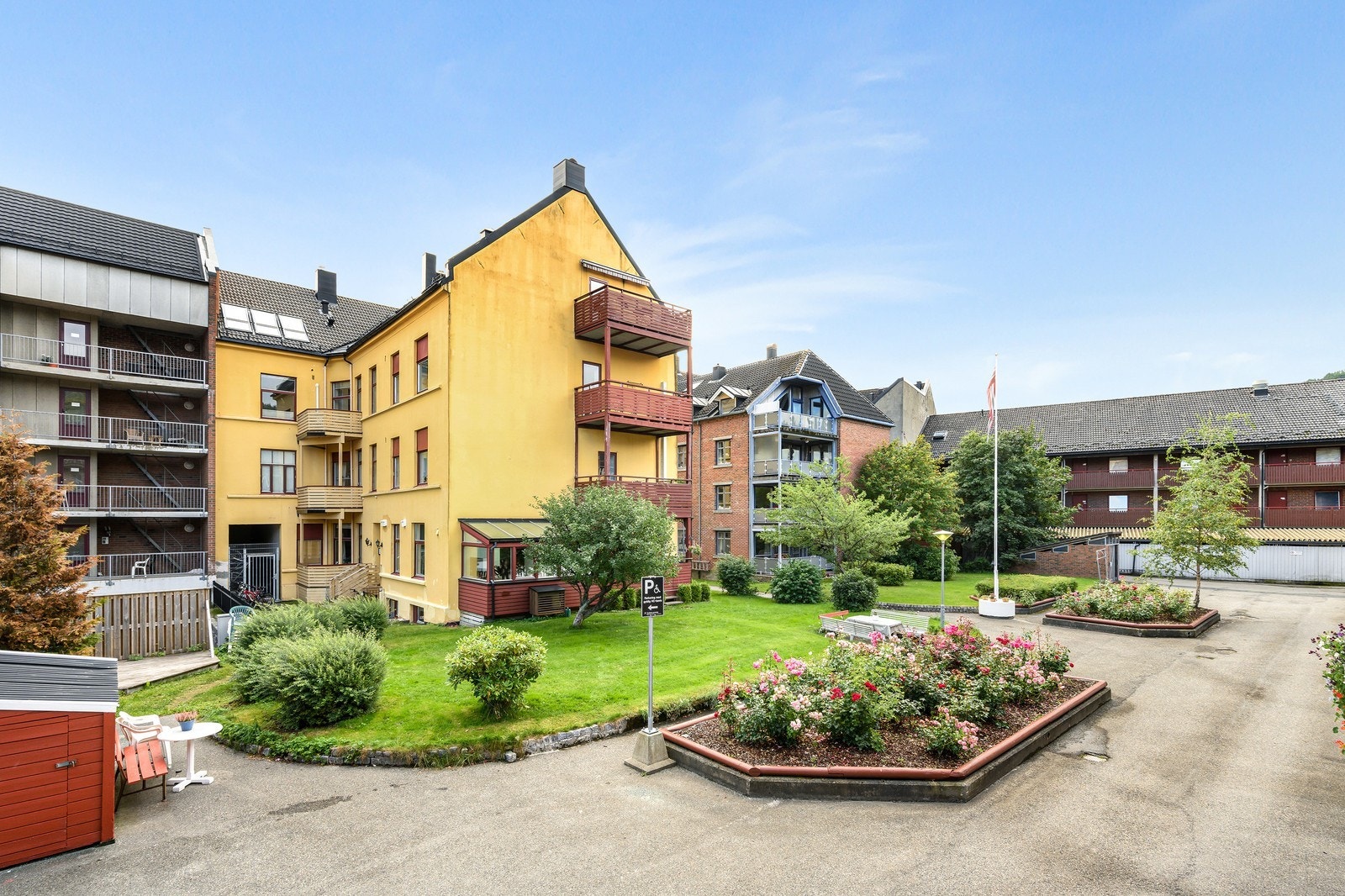Skjermet bakgård med grøntarealer. Inngangen er opp trappen på venstresiden av det gule bygget. Galleribilde