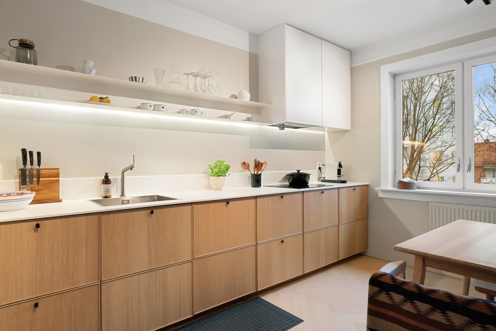 Kjøkkeninnredning fra 2019 med glatte fronter, laminat benkeplate og platekledning over benkeskap. Galleribilde