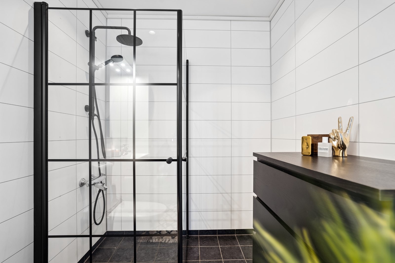 Innredningen er moderne med heldekkende servant, stilrene sorte detaljer og dusjløsning med innfellbare dører. Galleribilde